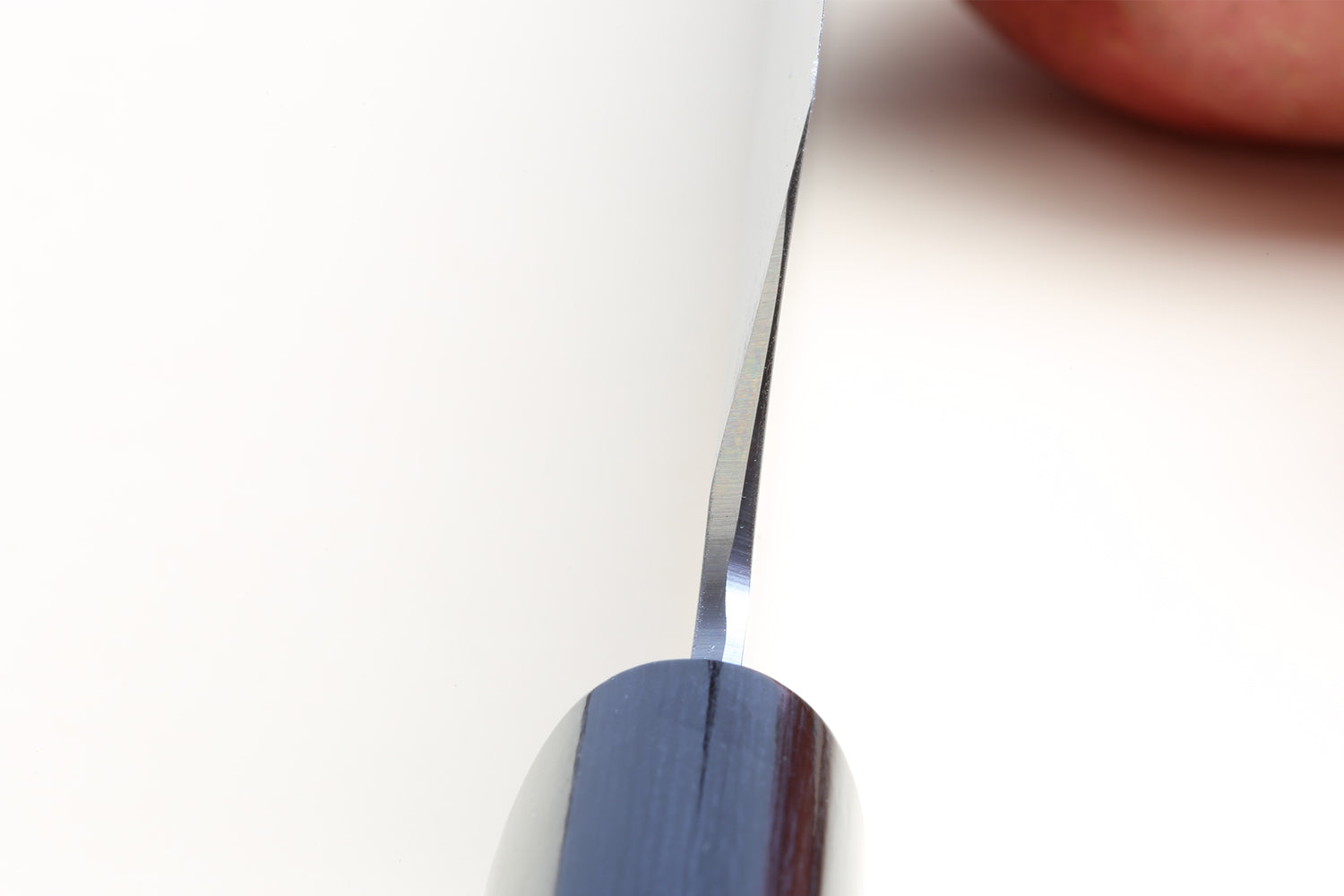 Knife blade close-up with silver cutting edge and dark spine near tip