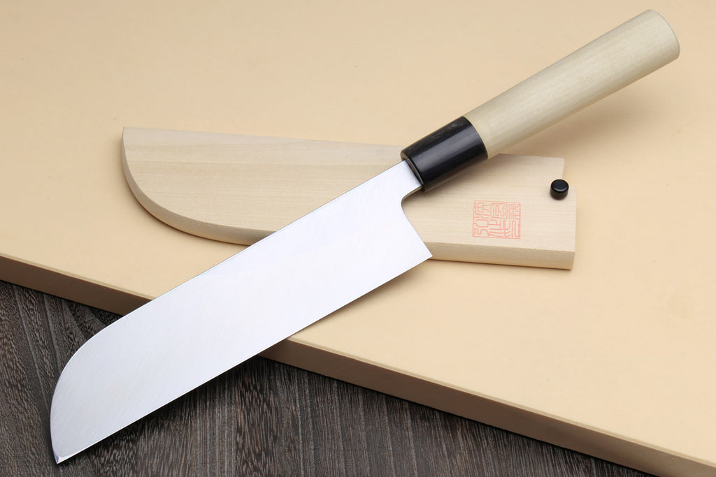 Japanese vegetable chef knife with dark blade and light wood handle, shown on wooden board.