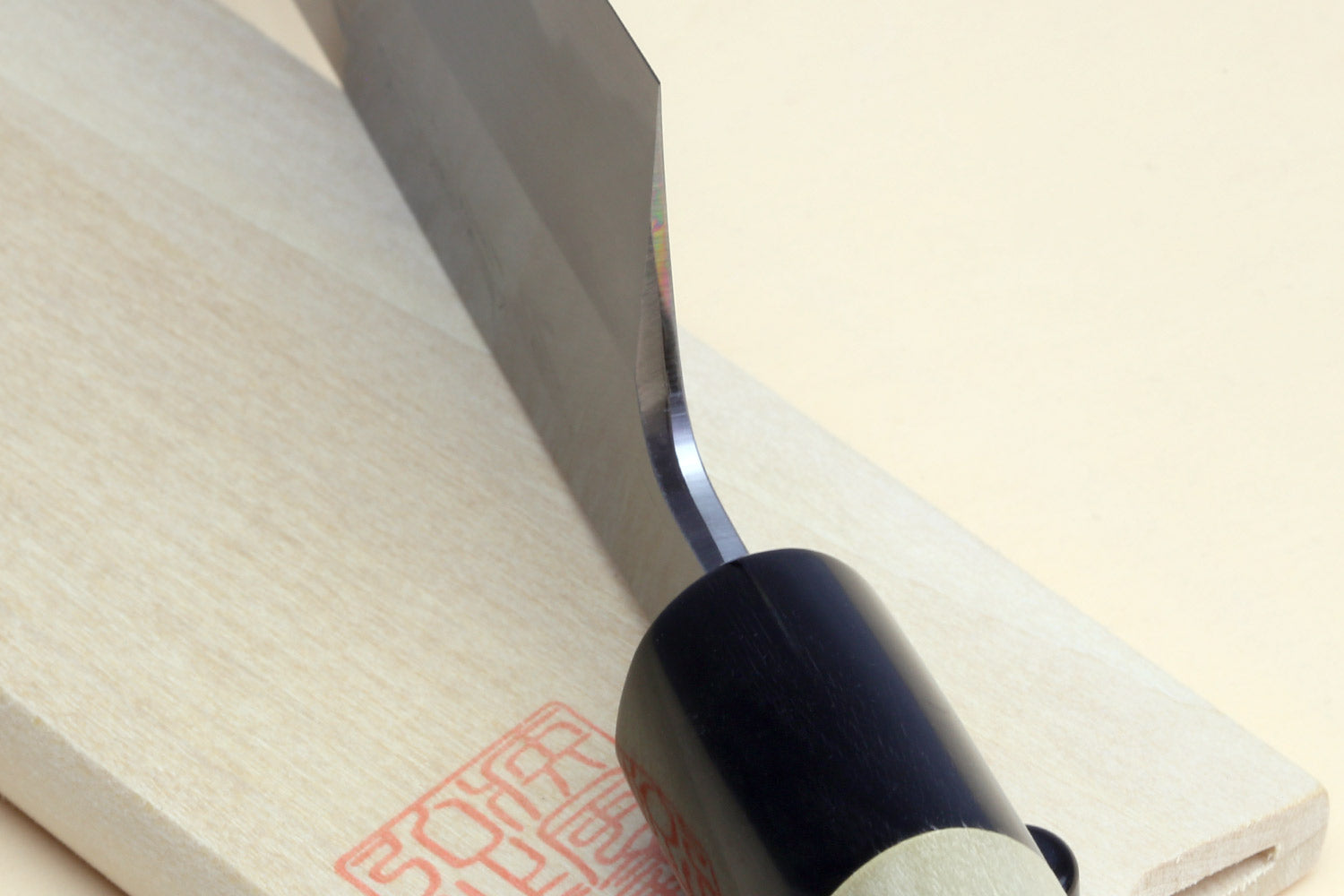 Japanese vegetable chef knife close-up: dark blade against light wood handle and black collar.