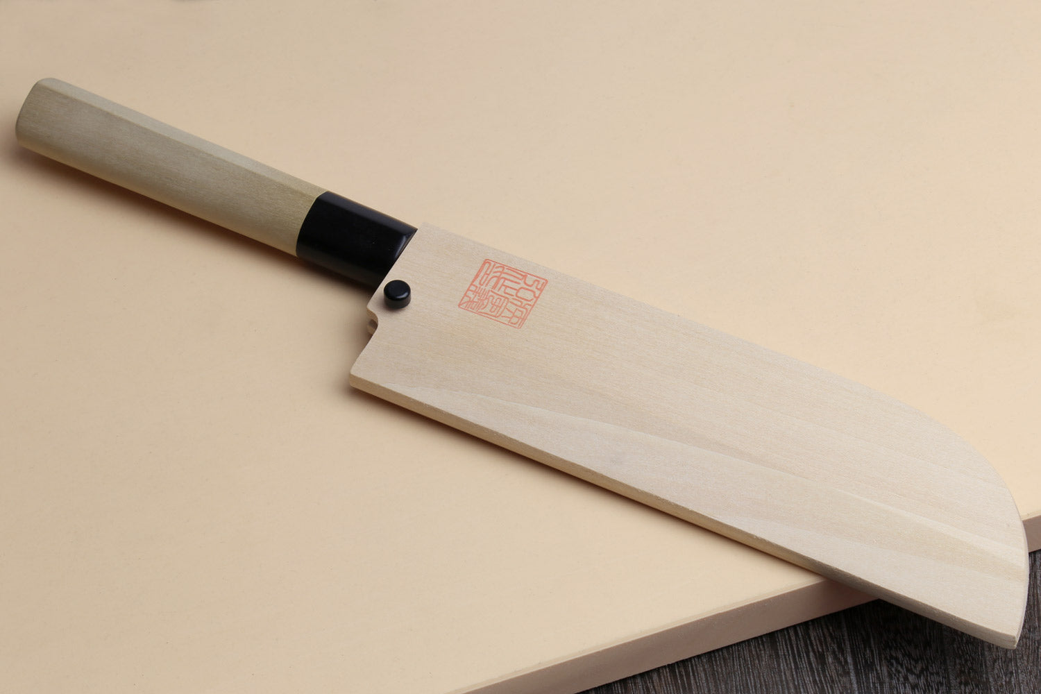 Japanese vegetable chef knife with dark blade and light wood handle, black grip end.