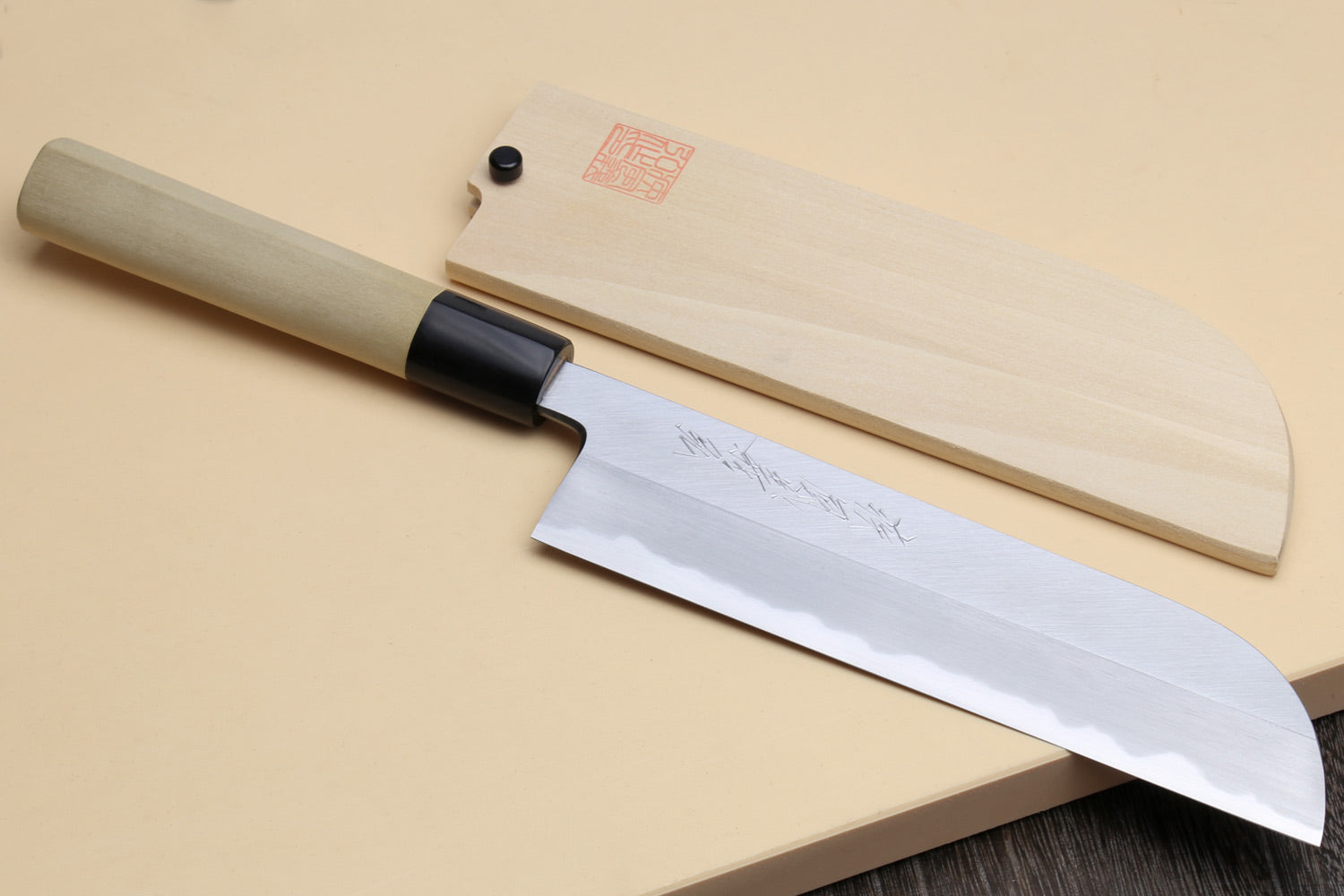 Japanese vegetable chef knife with dark blade and light wood handle, with matching sheath.