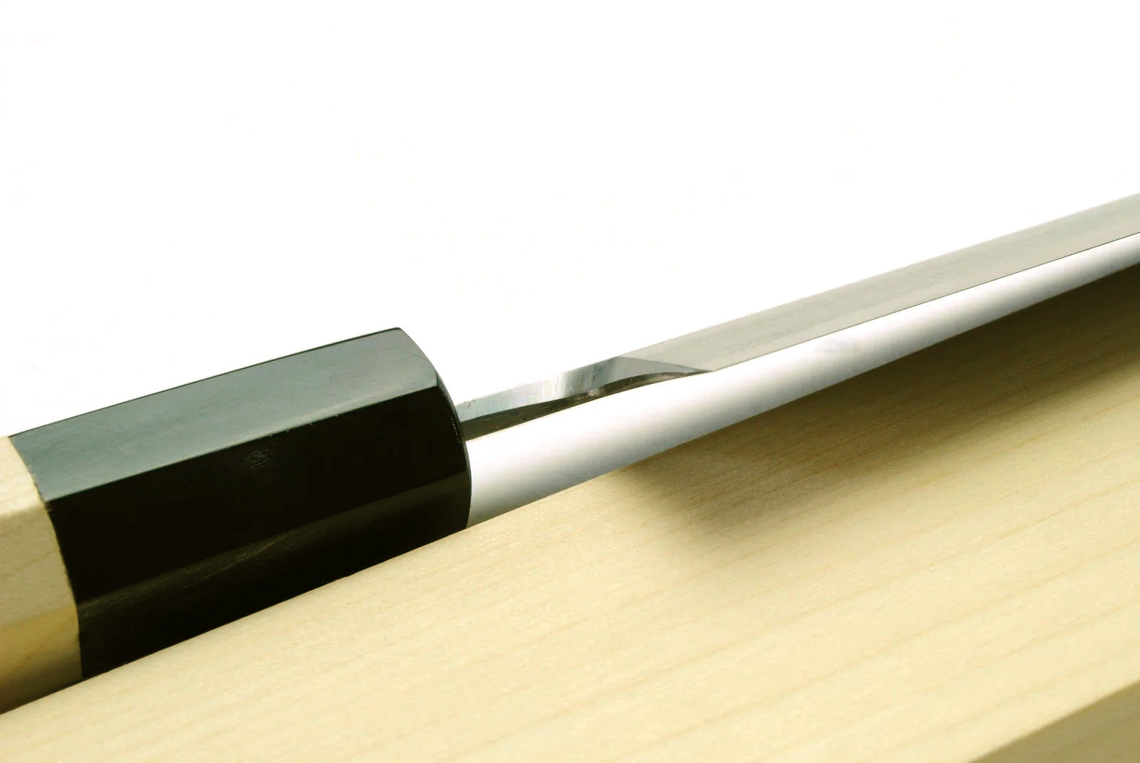 Japanese chef knife side view, white blade with reflective edge and black handle collar