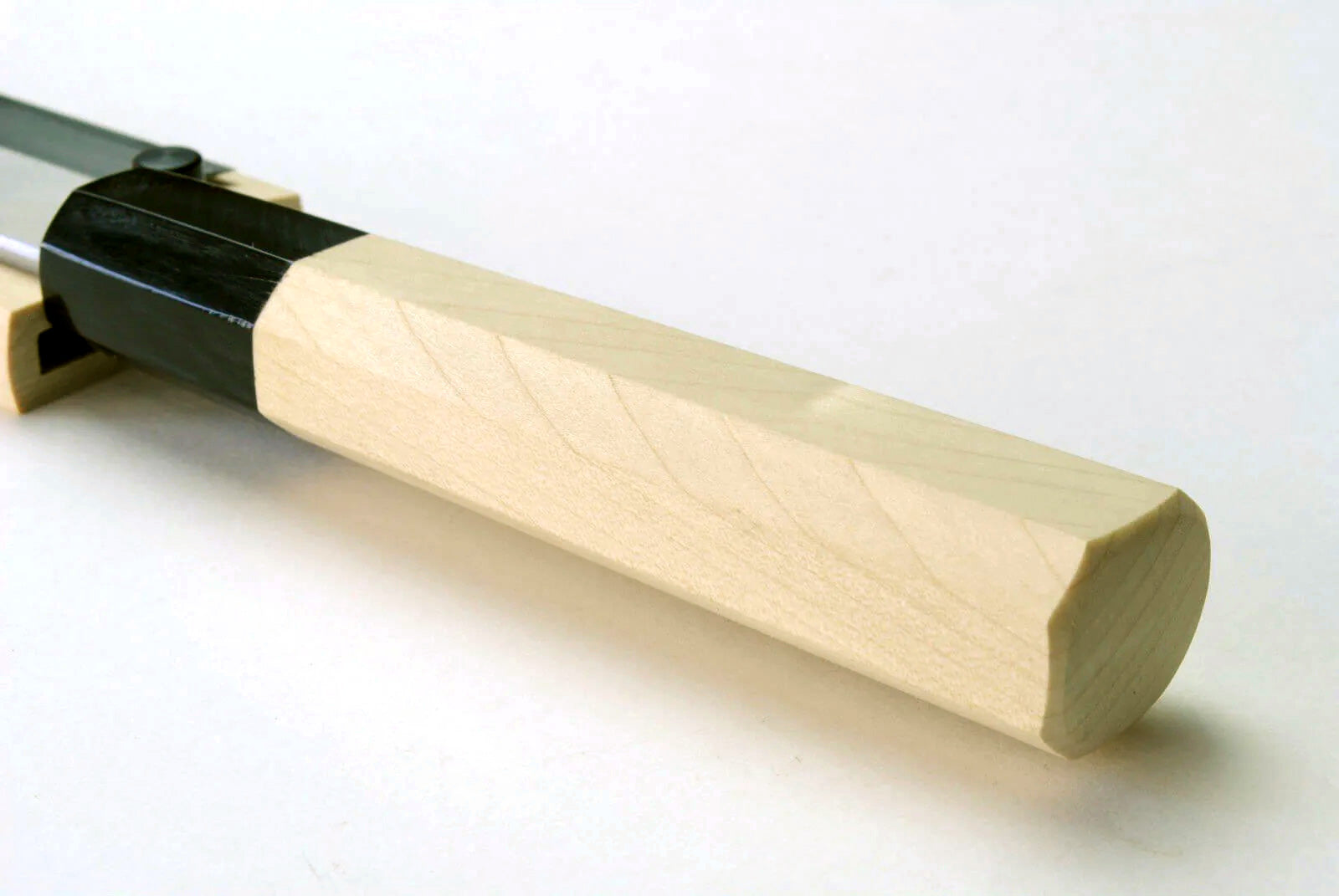Japanese chef knife handle end, pale wood grip with black collar and white blade