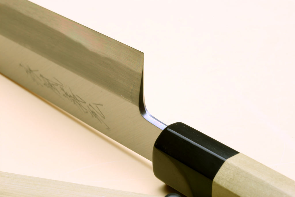 Japanese chef knife close-up of white steel blade and black collar near handle
