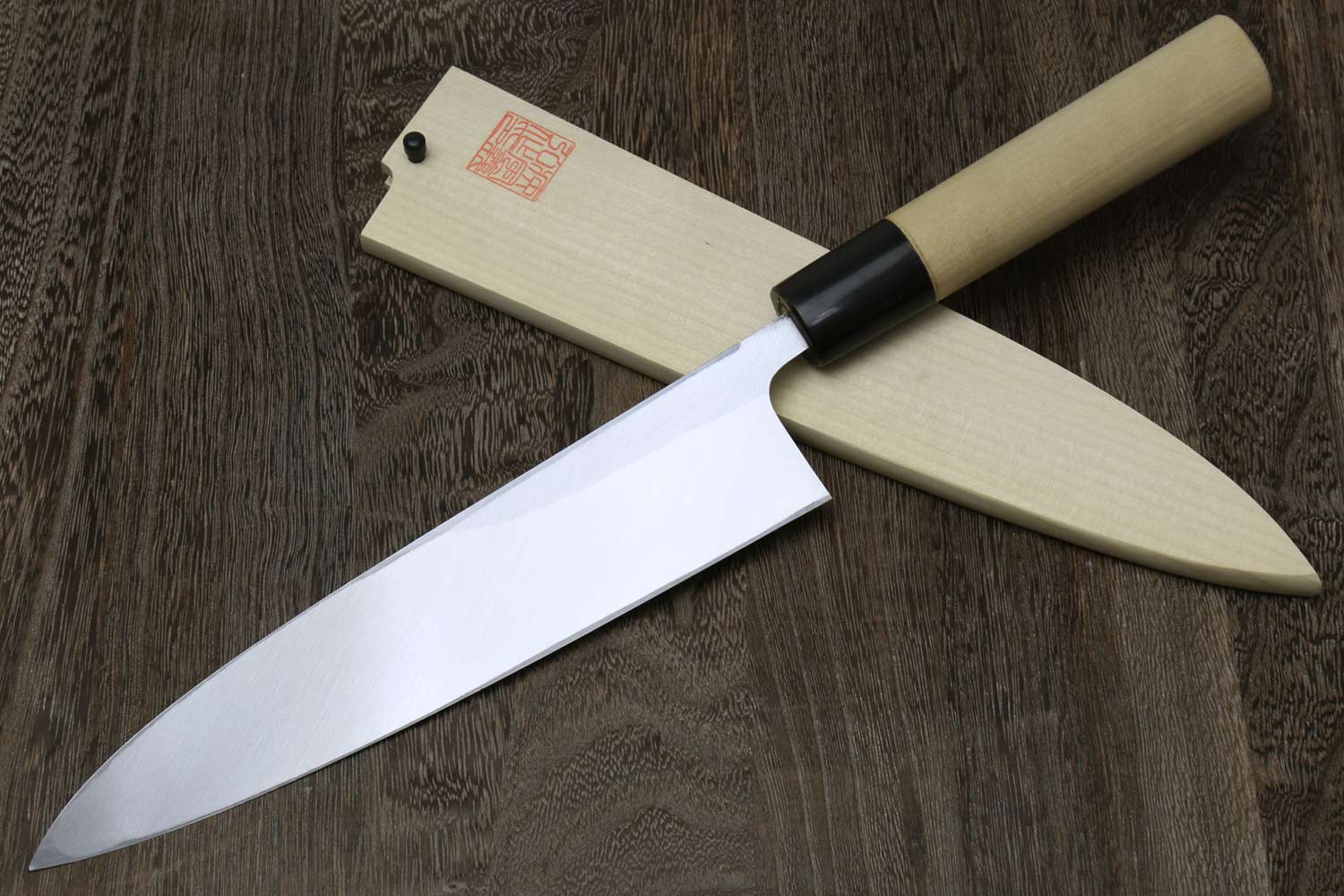 Japanese chef knife with light wood handle and silver blade, black bolster