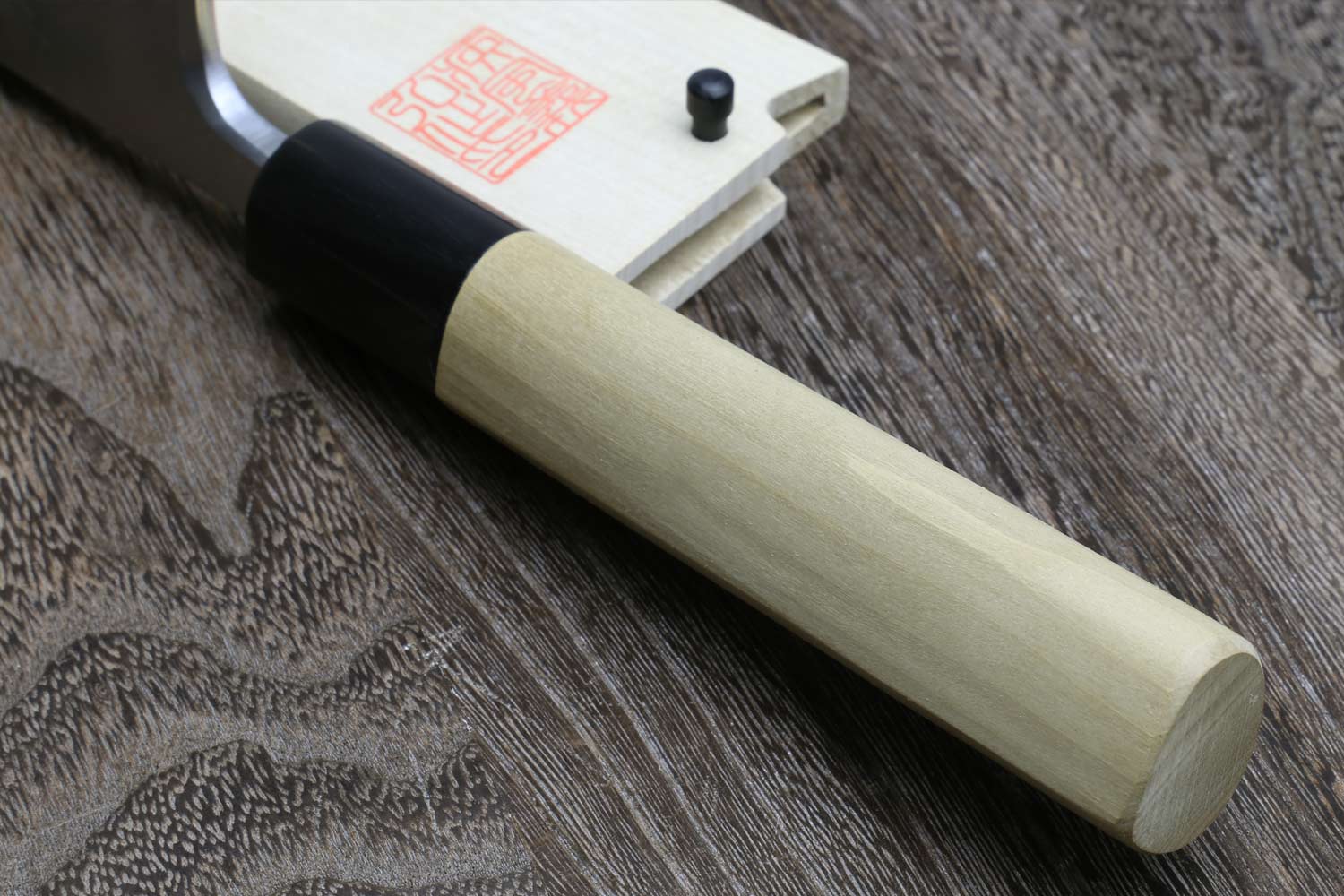 Japanese chef knife close-up with light wood handle and silver blade root