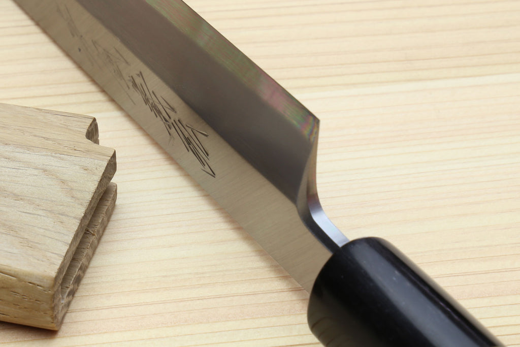 Yanagi knife partly in saya, showing blade edge and rosewood handle