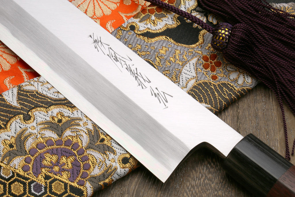 White steel vegetable knife blade with engraved markings; dark handle edge