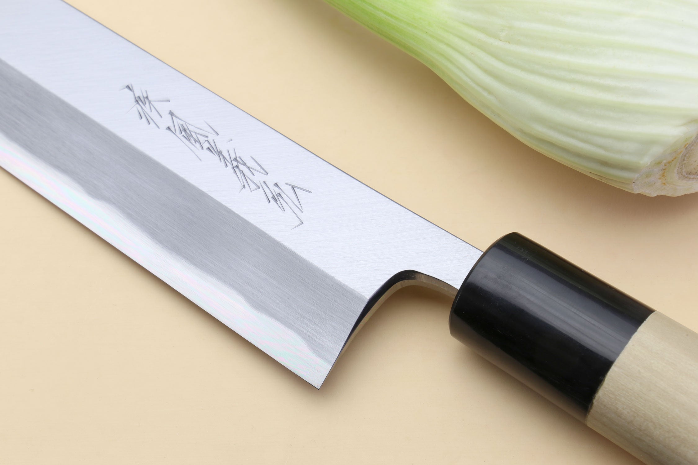 Close-up of silver blade with etched markings and black handle hardware