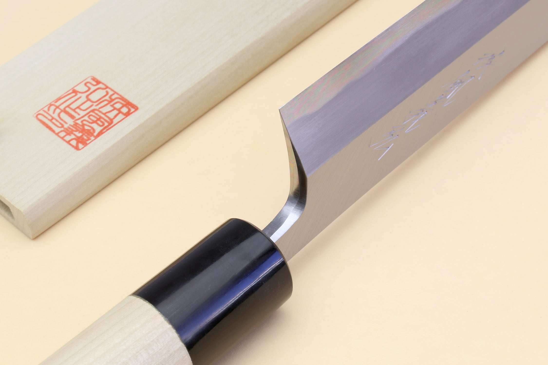 Knife handle with light wood grip, black ferrule, and red stamp on blade