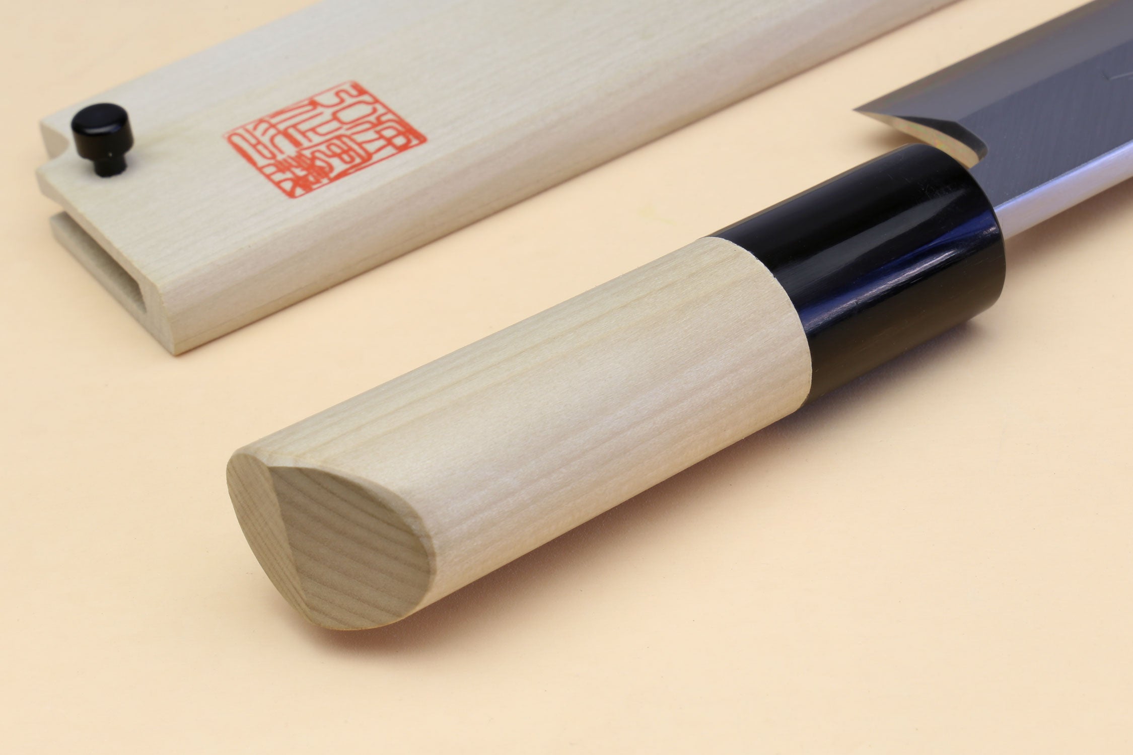 Light wood handle with rounded end and black bolster beside silver blade