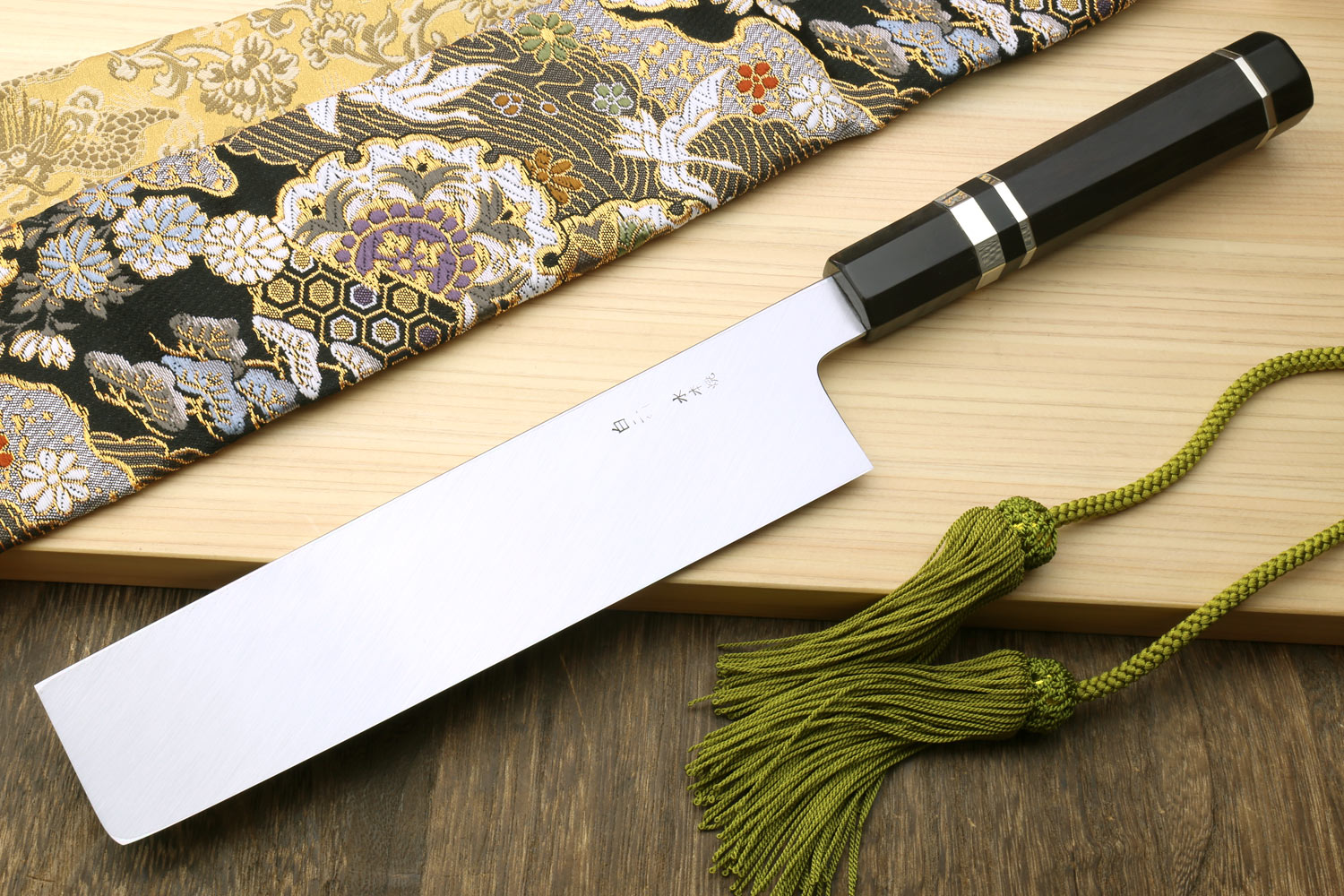 Japanese vegetable knife with dark checkered handle sleeve, polished blade on cloth