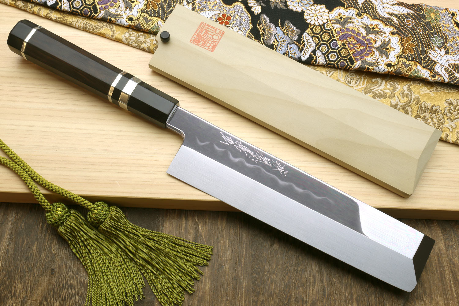 Japanese vegetable knife with etched blade and dark handle, wooden saya and cord