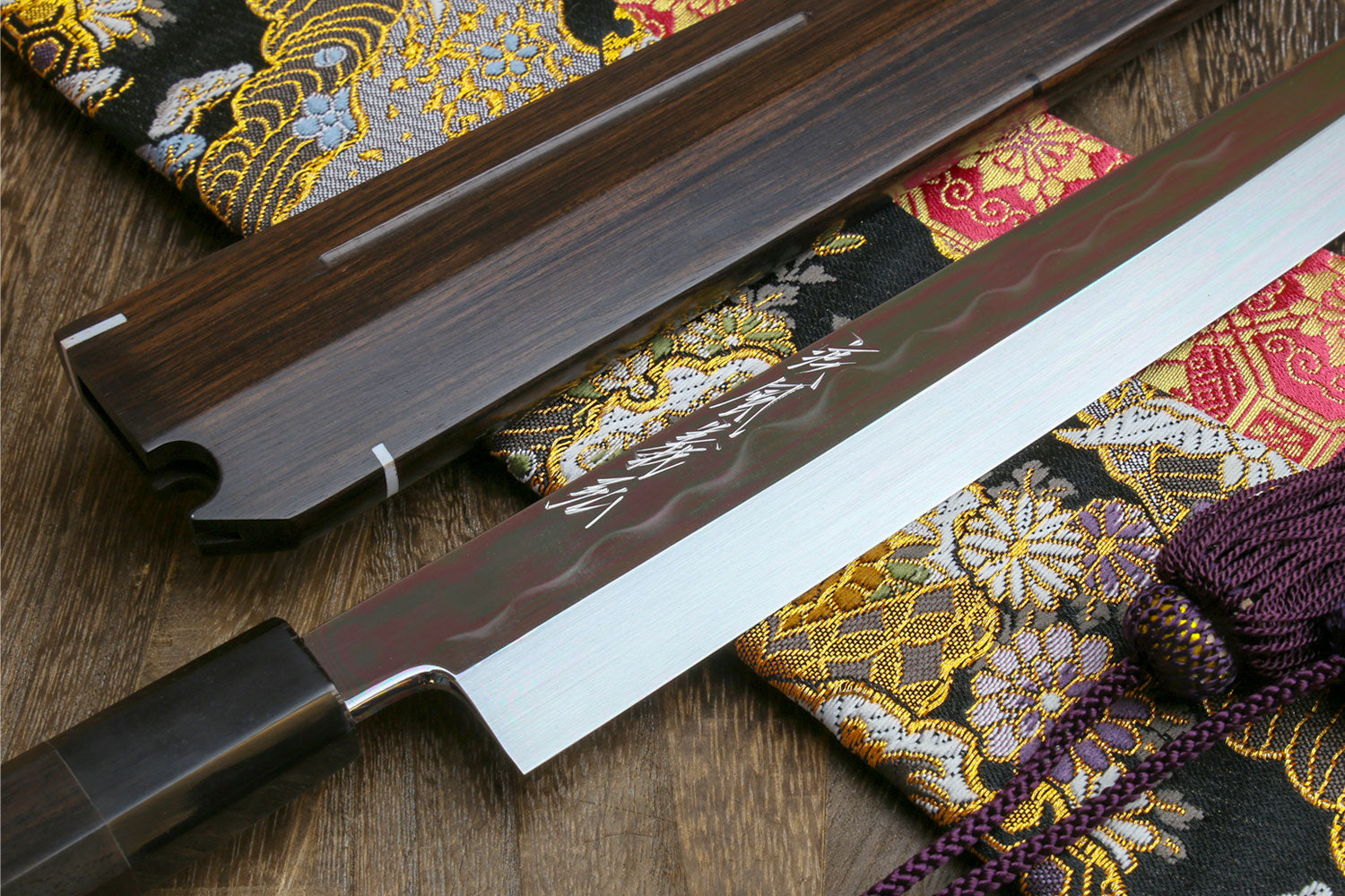 Japanese sushi knife with mirror-finished white blade and dark wooden saya