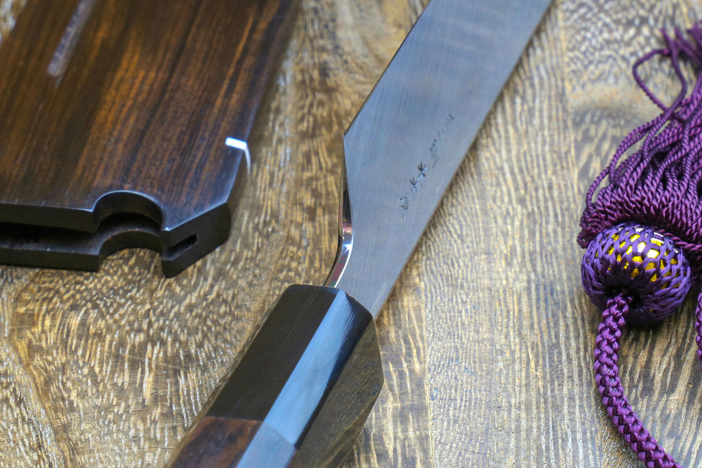 Japanese sushi knife with black handle, saya, and mirror-finished steel blade