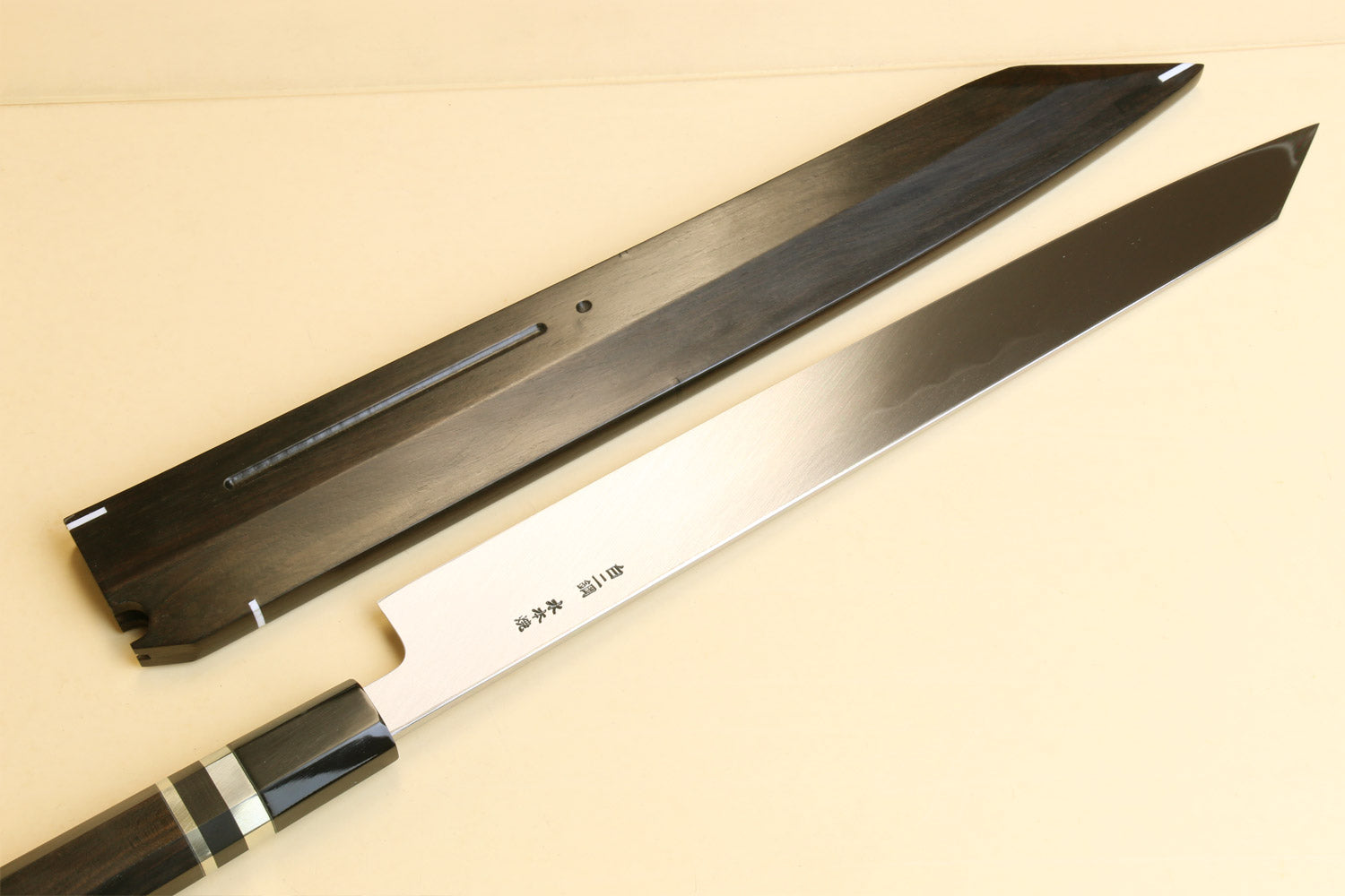 Japanese yanagi knife with long silver blade and dark wooden saya