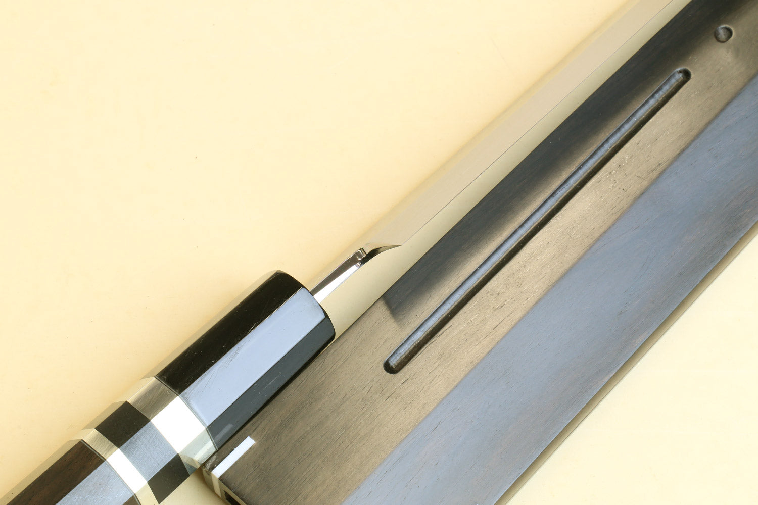 Yanagi knife detail: dark handle with silver checkered ferrule and long blade