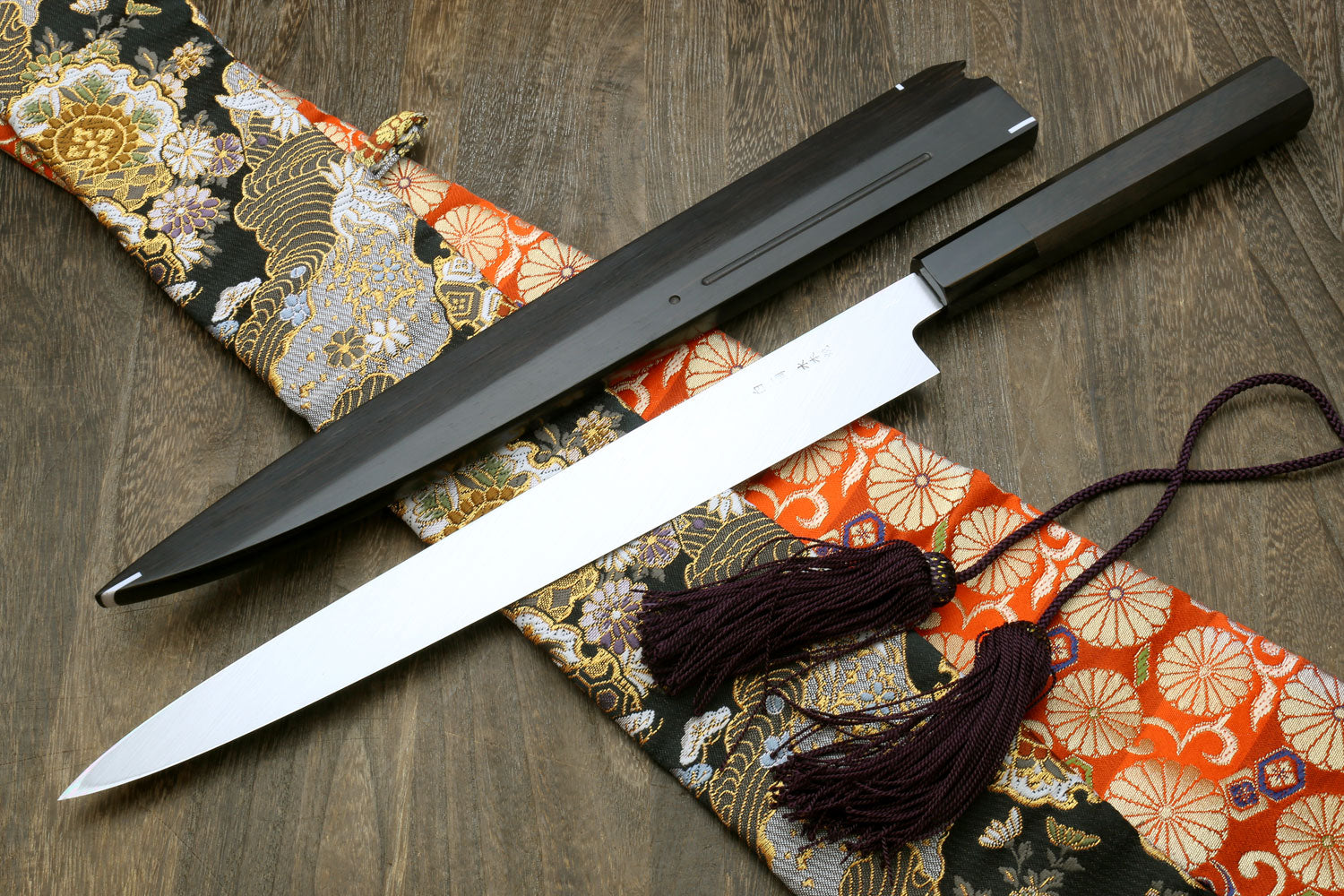 Sashimi knife and saya with mirror-finished blade, on patterned fabric wrap with cord