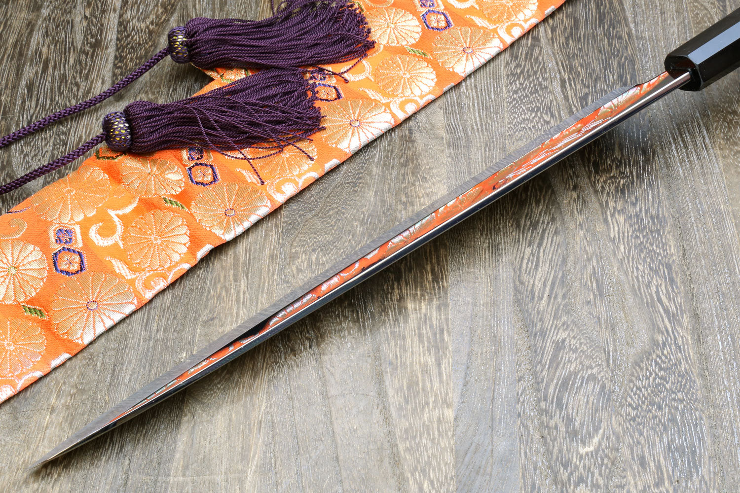Sashimi knife in saya on patterned fabric, dark handle and purple cord tassel