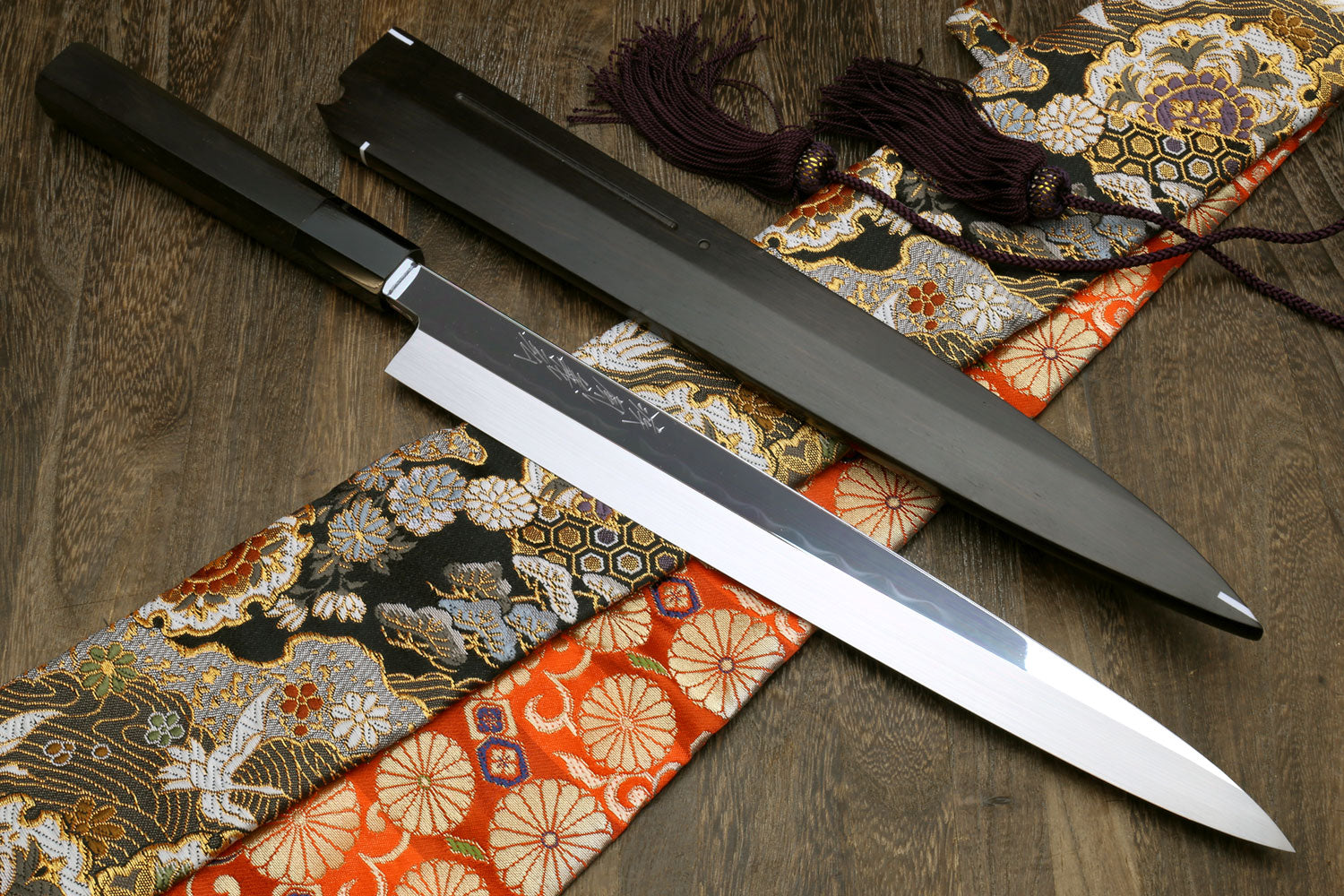 Sashimi knife with mirror-finished blade and dark saya, patterned fabric wrap and purple cord