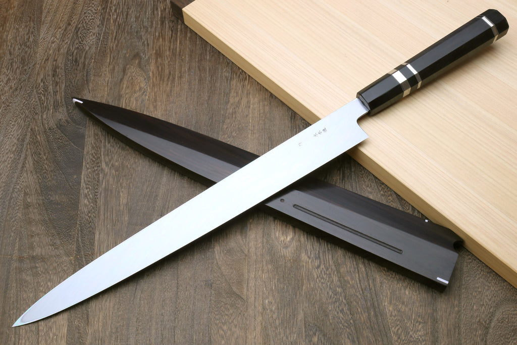 Japanese sushi knife with reflective blade, dark handle, and black saya