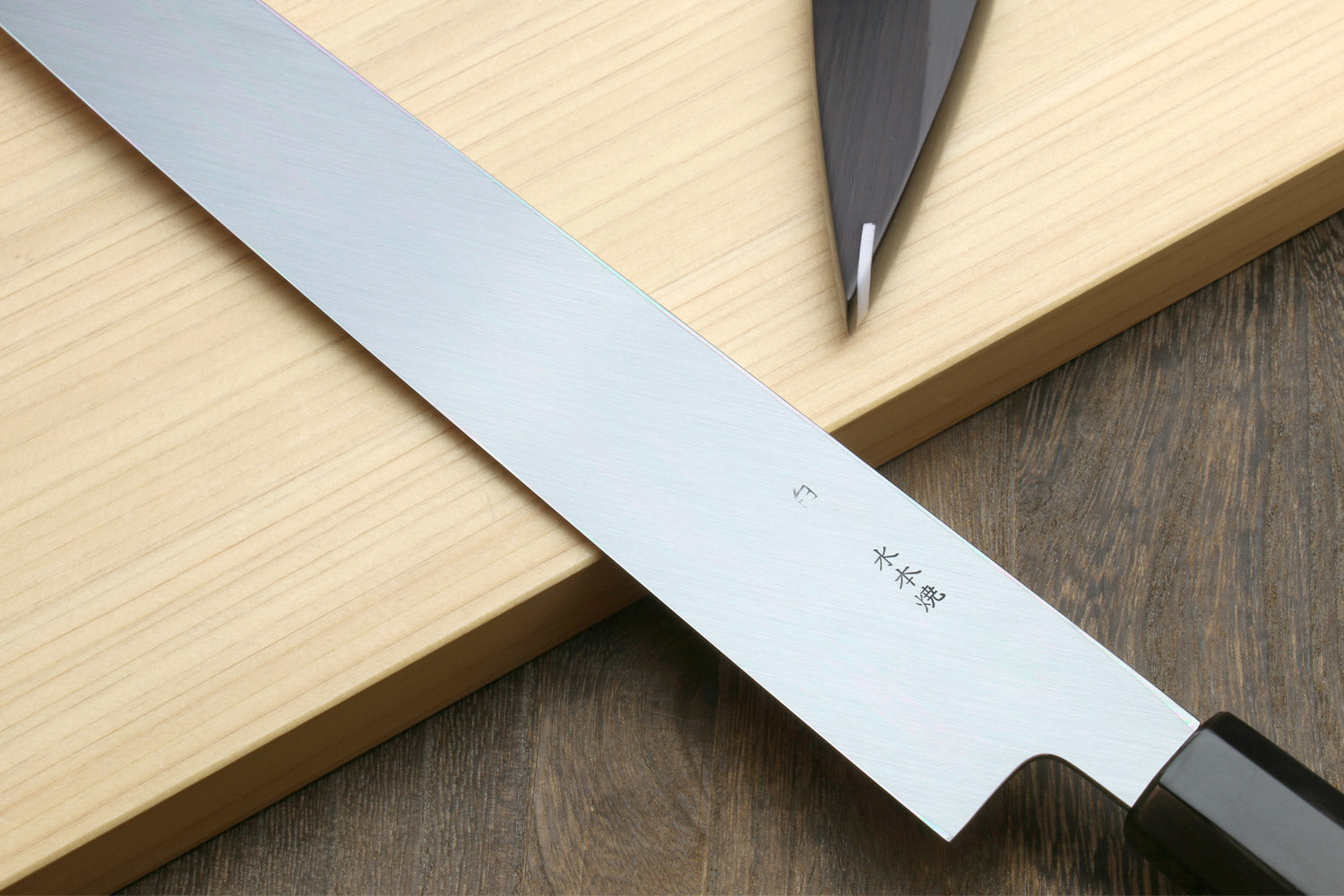 Sashimi knife blade close-up with fine edge and dark handle