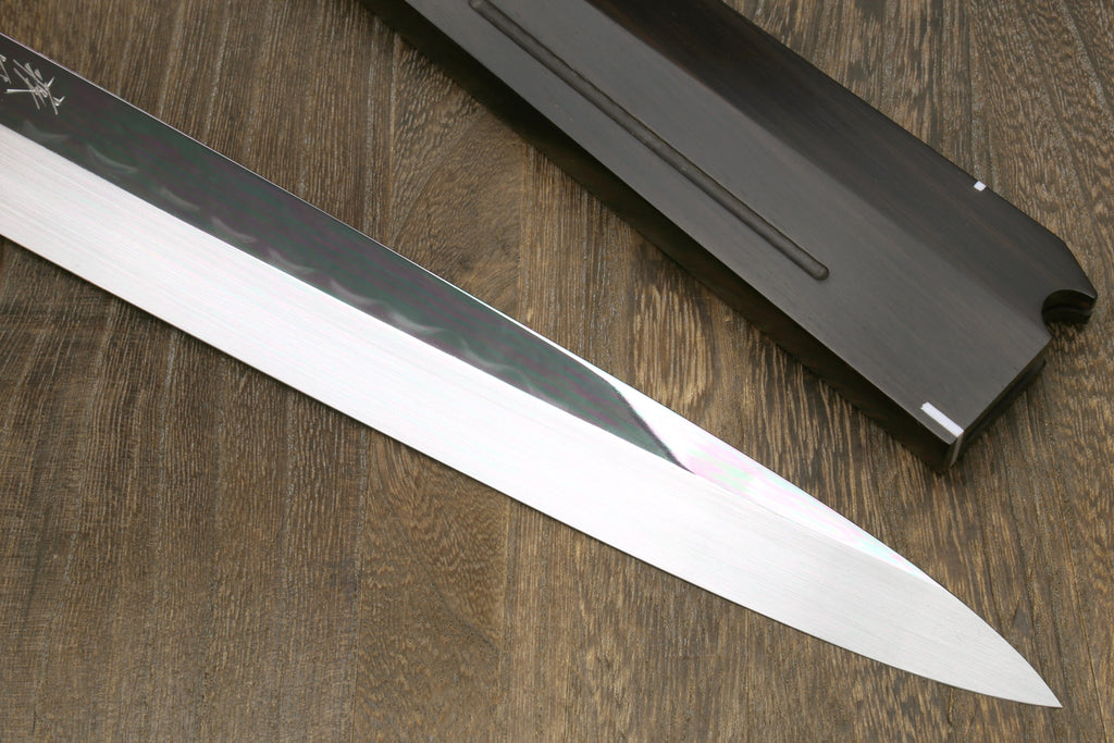 Mirror-finished sashimi knife blade with dark sheath and pointed tip