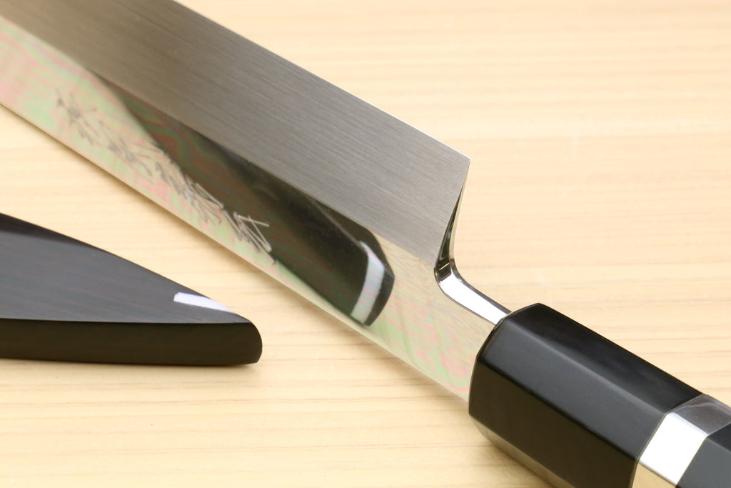 Sashimi knife close-up: silver ring at dark handle with polished blade