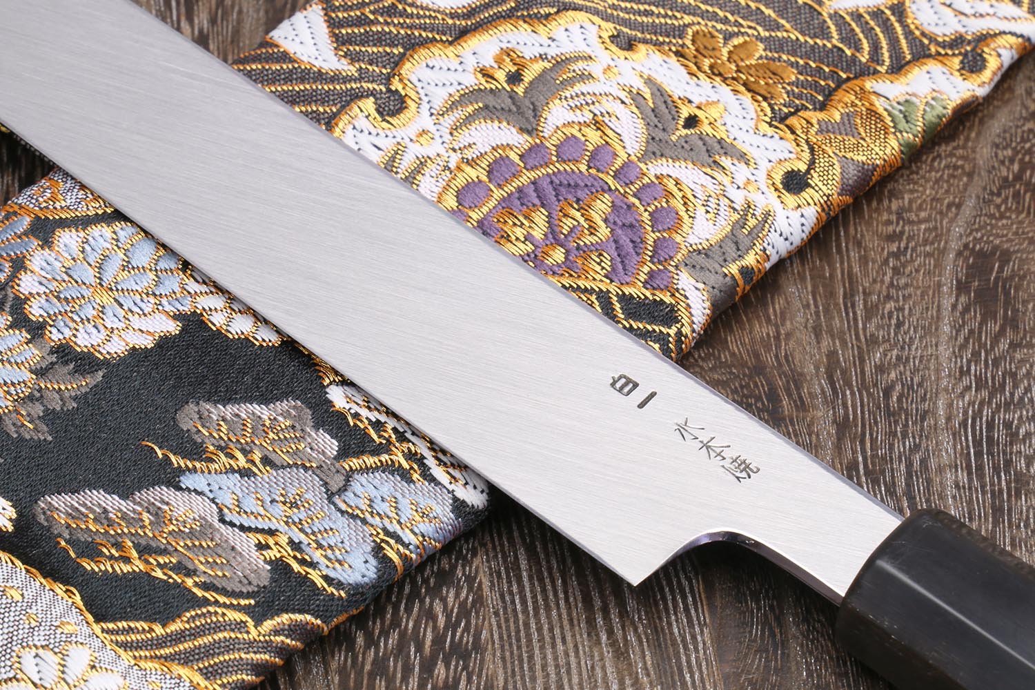 Yanagi knife blade close-up showing etched text and mirror-finished edge