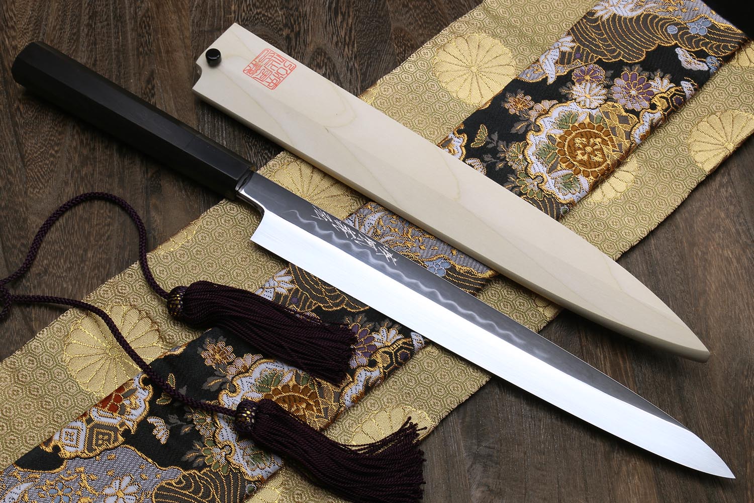 Yanagi knife on patterned fabric with tassel ties, white blade and dark handle