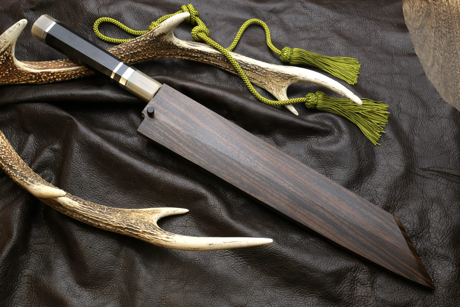 Kiritsuke knife with dark handle, horn sheath, and green cord tassel.