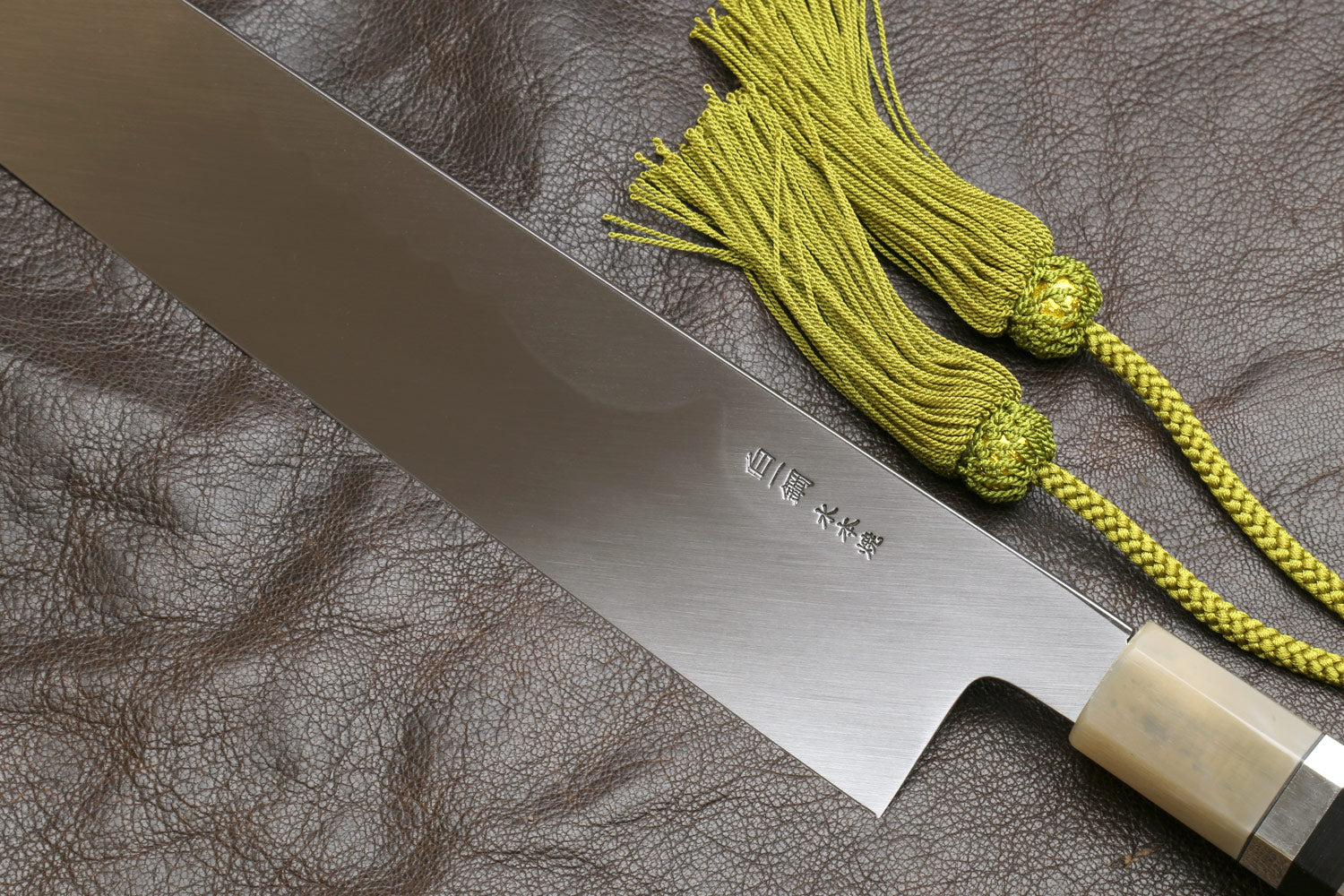 Kiritsuke knife with mirror-polished blade, ivory handle, green tassel cord.