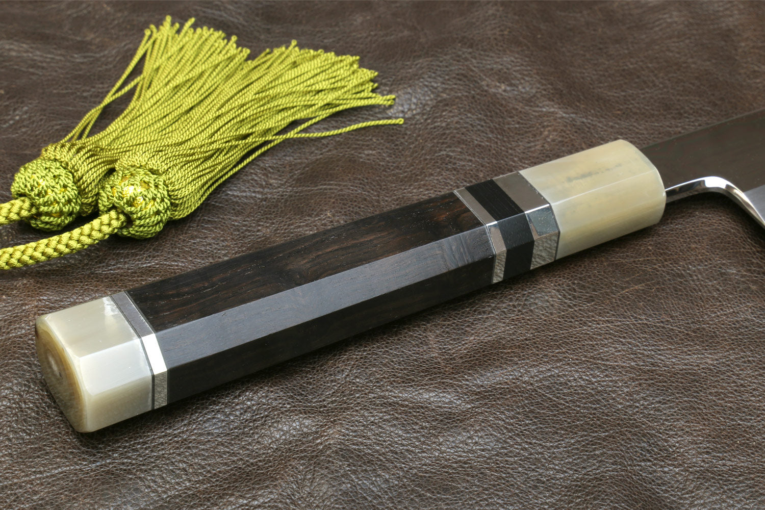 Knife handle with ivory grip and dark guard, with green tassel cord.