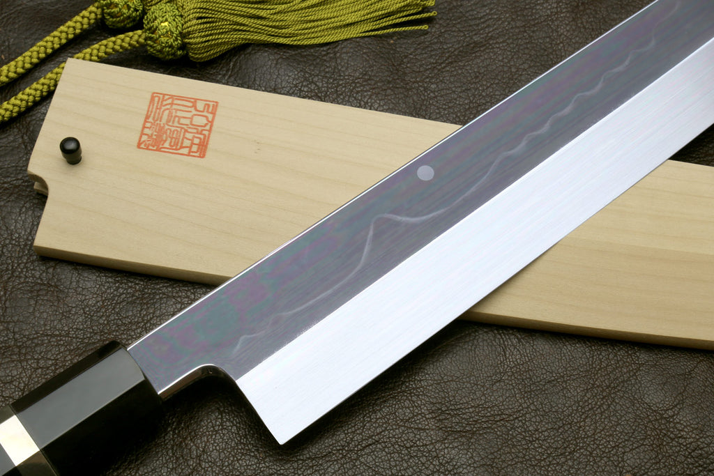 Japanese-style kitchen knife with wavy mirror-polished steel blade and light wood sheath