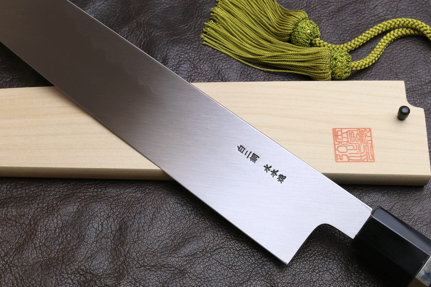 Japanese-style kitchen knife with wavy steel blade and engraved text on light steel edge