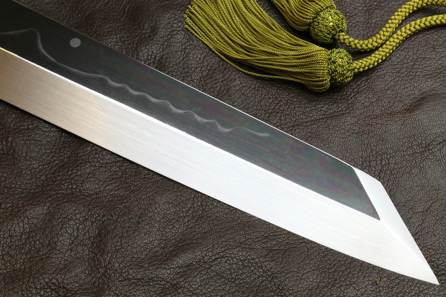 Japanese-style kitchen knife with dark handle and long pointed wavy steel blade