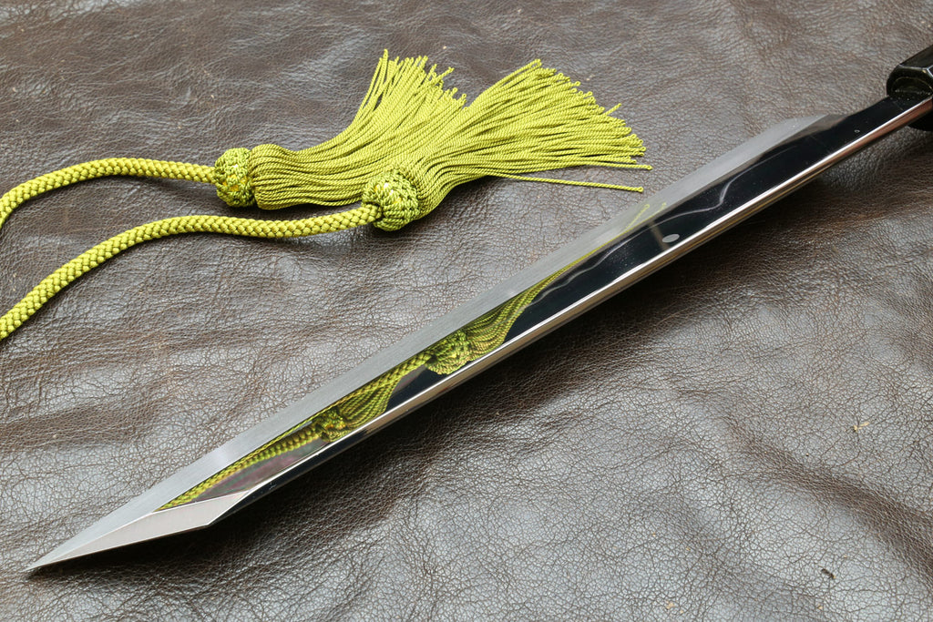 Japanese-style kitchen knife with wavy steel blade, dark handle, and green tassel cord
