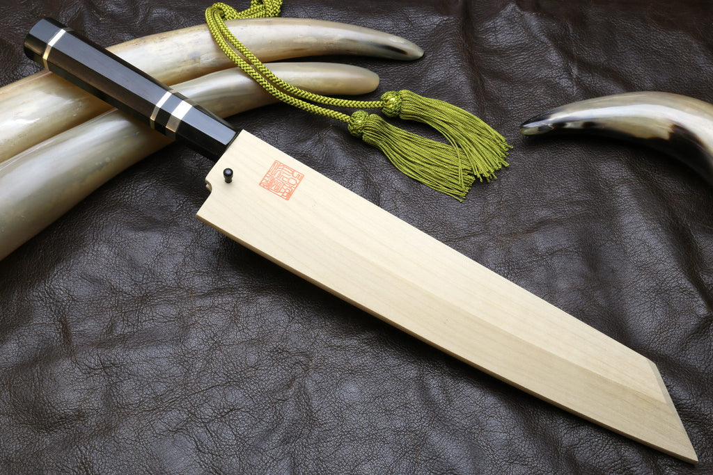 Japanese-style kitchen knife with wavy steel blade and light wood sheath, green cord tassel