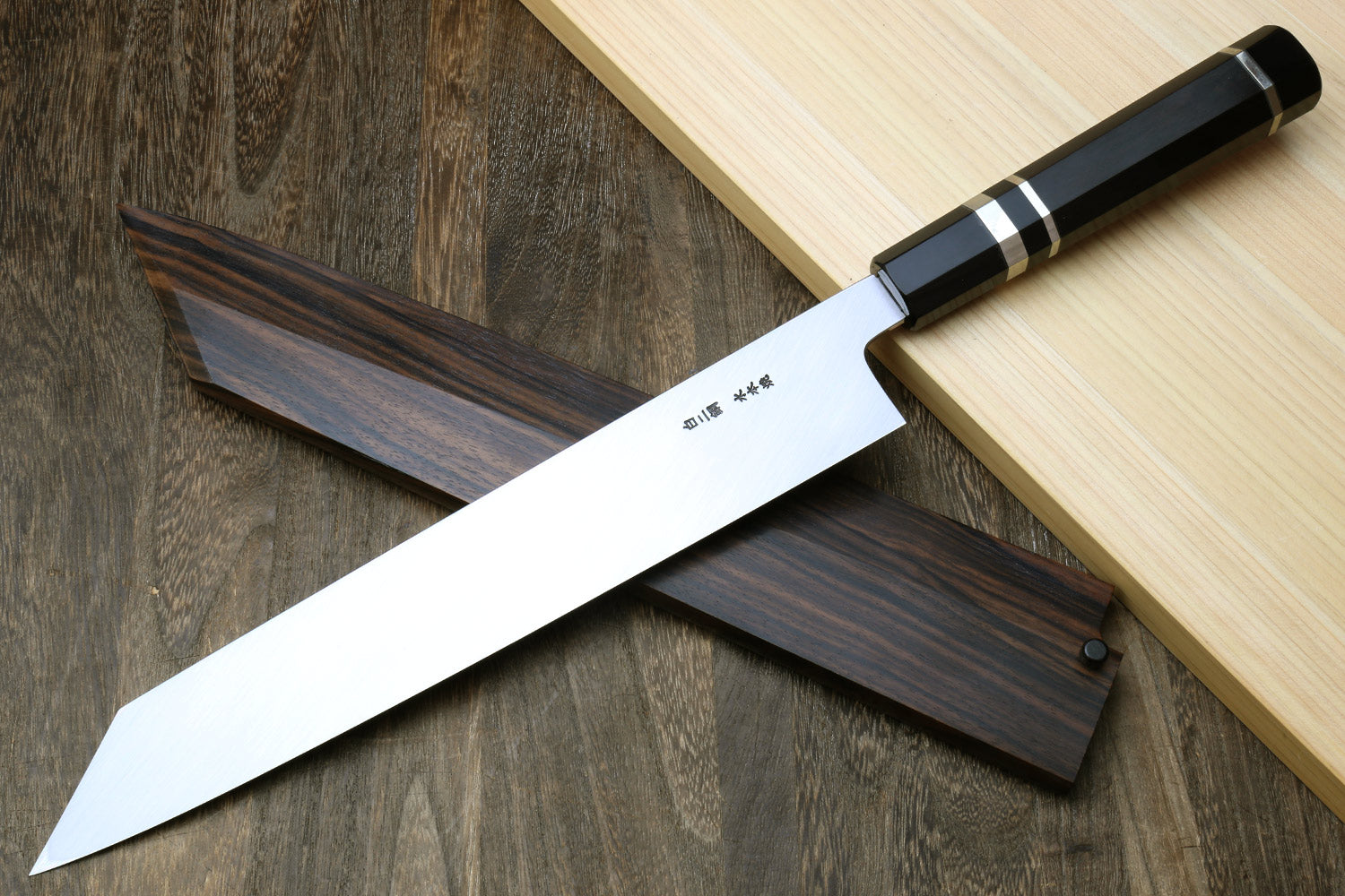 Ebony-handled kiritsuke chef knife with white blade and matching dark saya sheath
