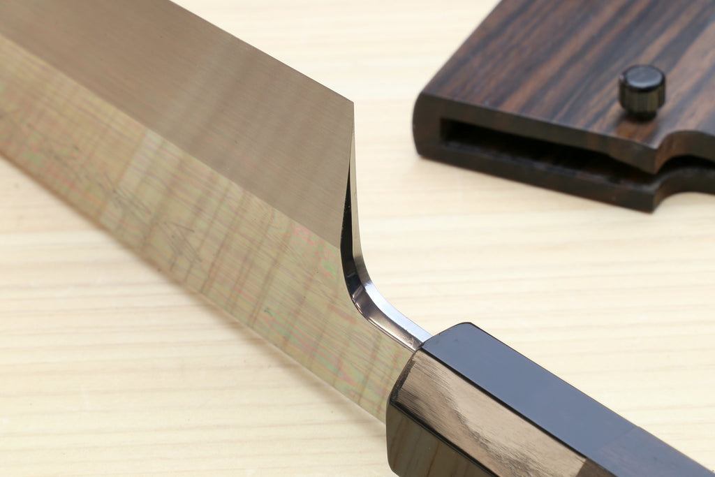 Japanese kitchen knife tip with curved cutting edge beside ebony saya