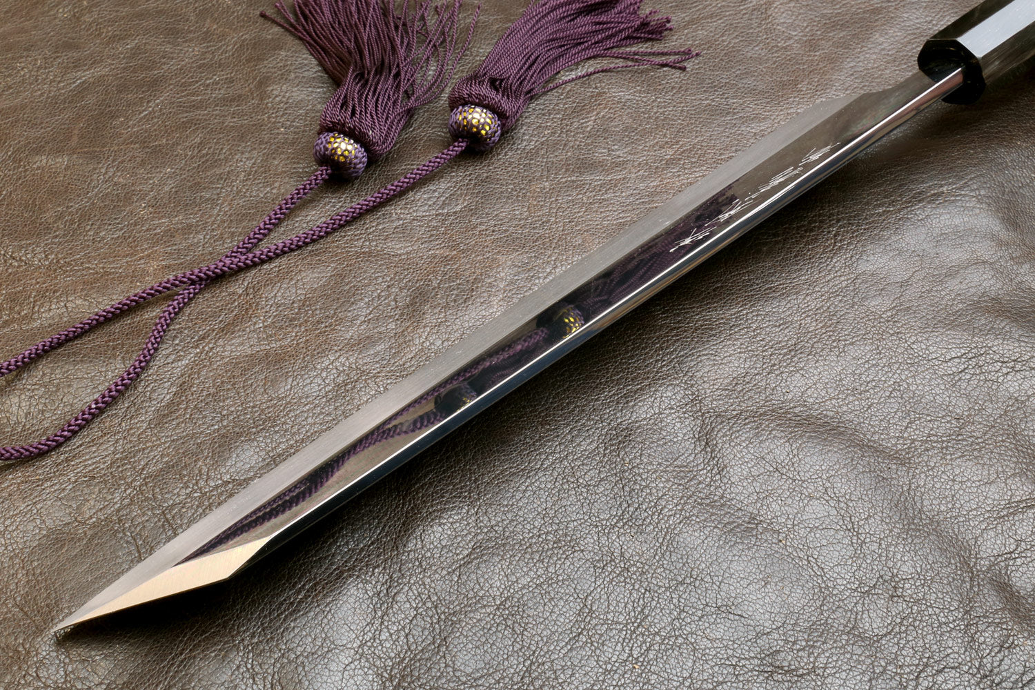 Kiritsuke knife with ebony handle and mirror-polished blade, angled close view