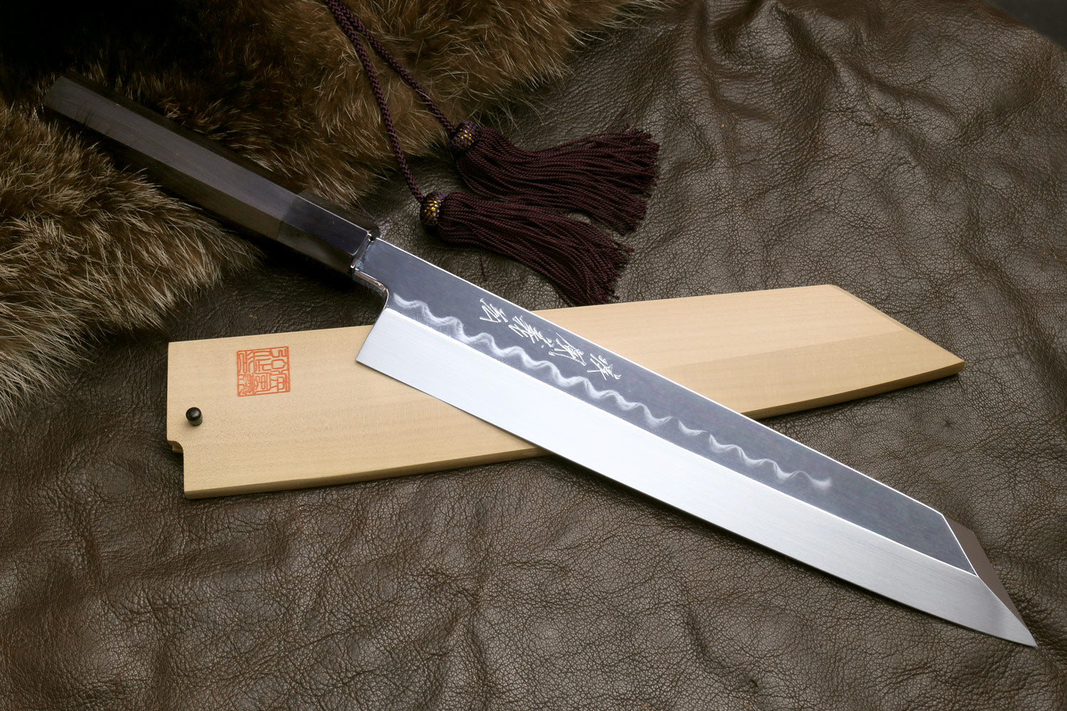 Kiritsuke knife with light saya and mirror-polished blade showing wavy hamon