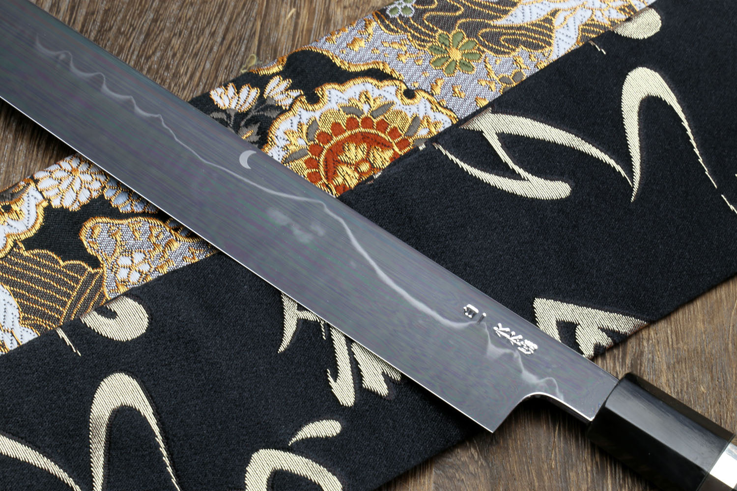 Mirror-finished Japanese kitchen knife with dark handle and silver-toned bolster