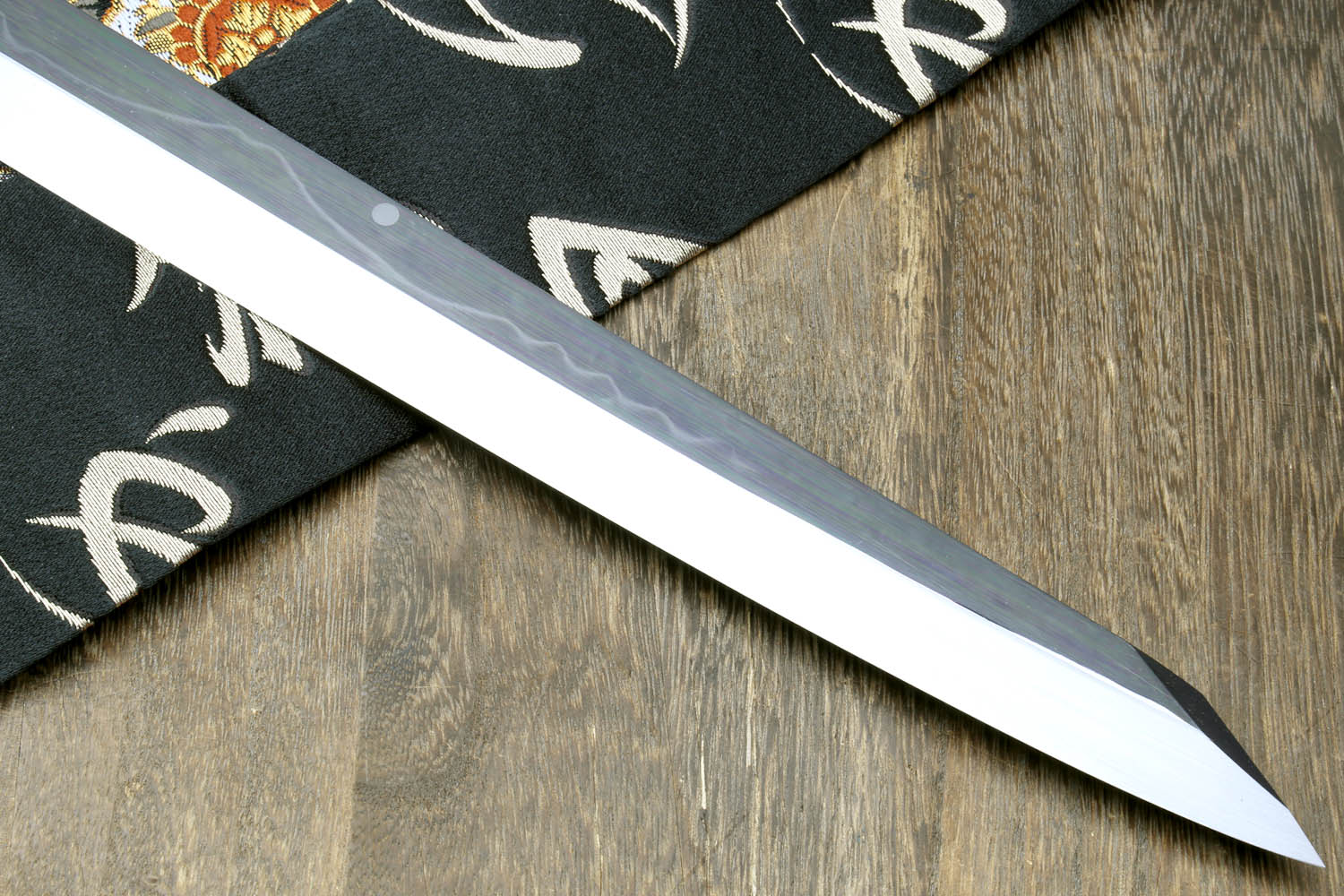 Mirror-finished Japanese kitchen knife blade with dark handle edge detail