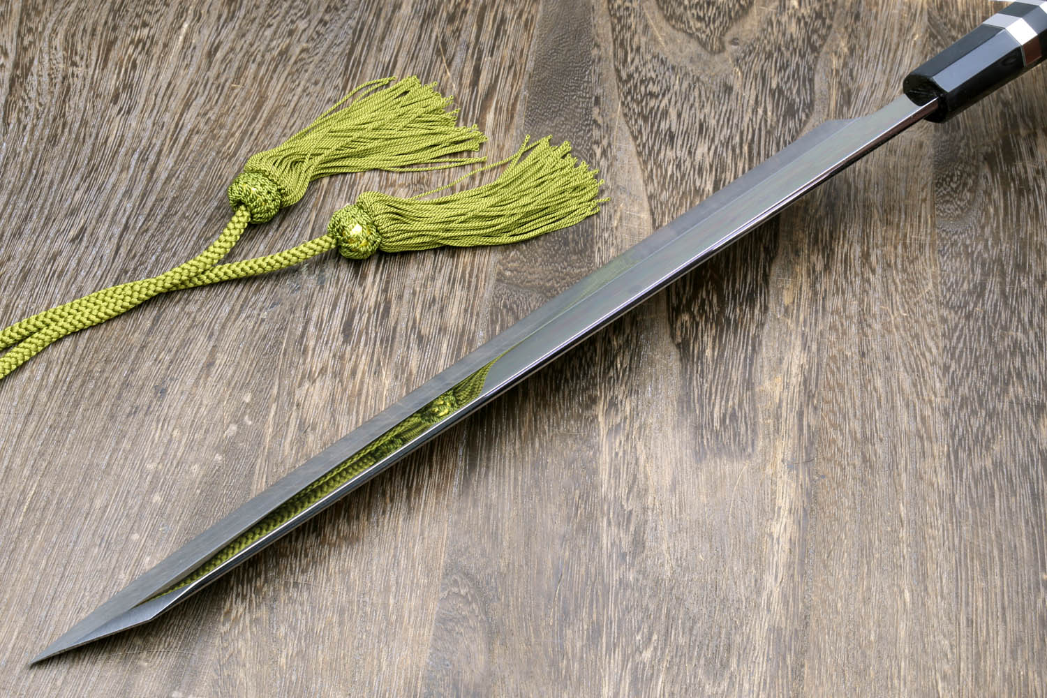 Mirror-finished Japanese knife with dark handle, green cord, and black cloth wrap