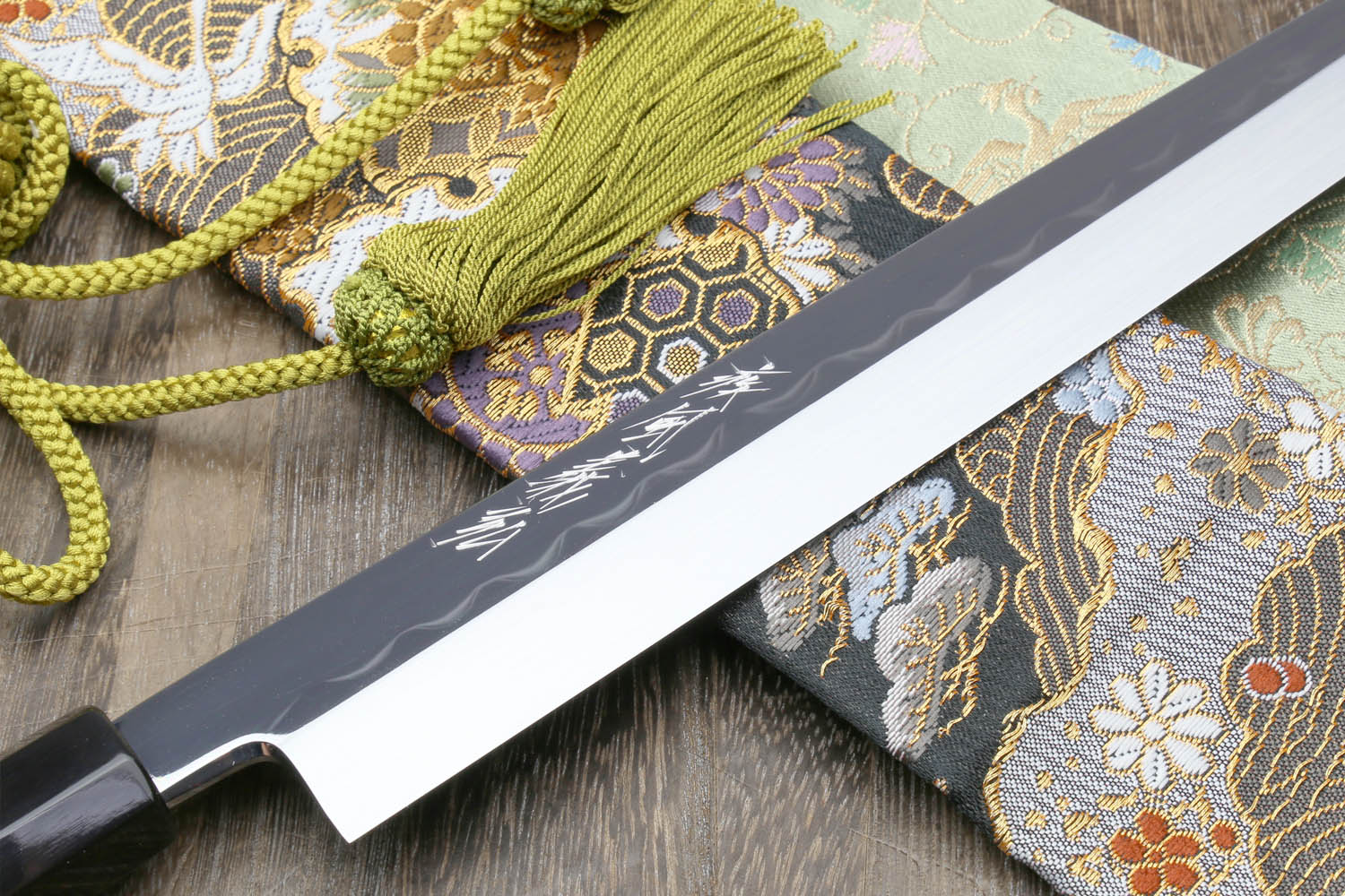 Japanese kitchen knife, mirror blade edge detail and black sheath with green cords