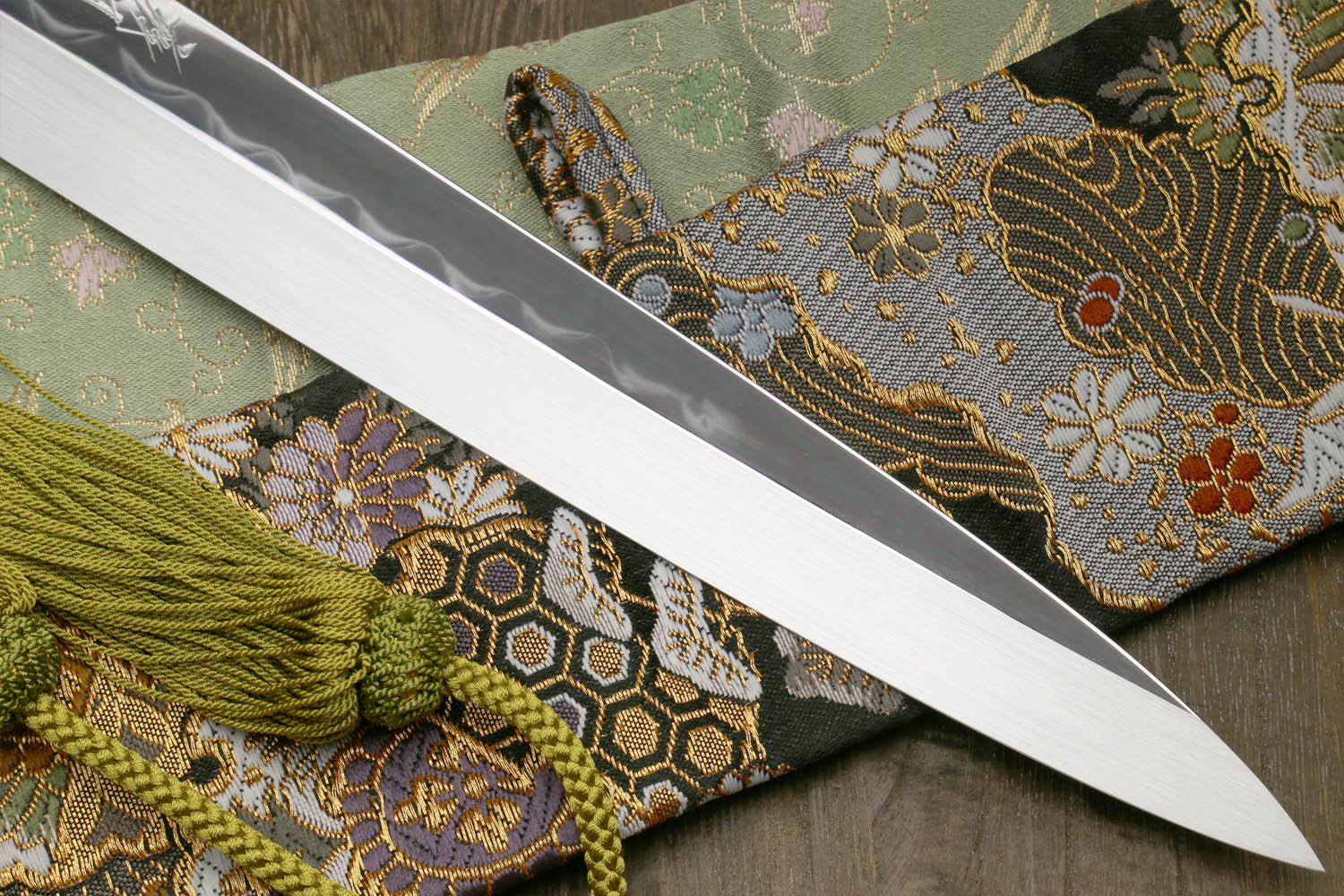 Japanese kitchen knife with mirror blade, ornate cloth sheath and green braided tassel