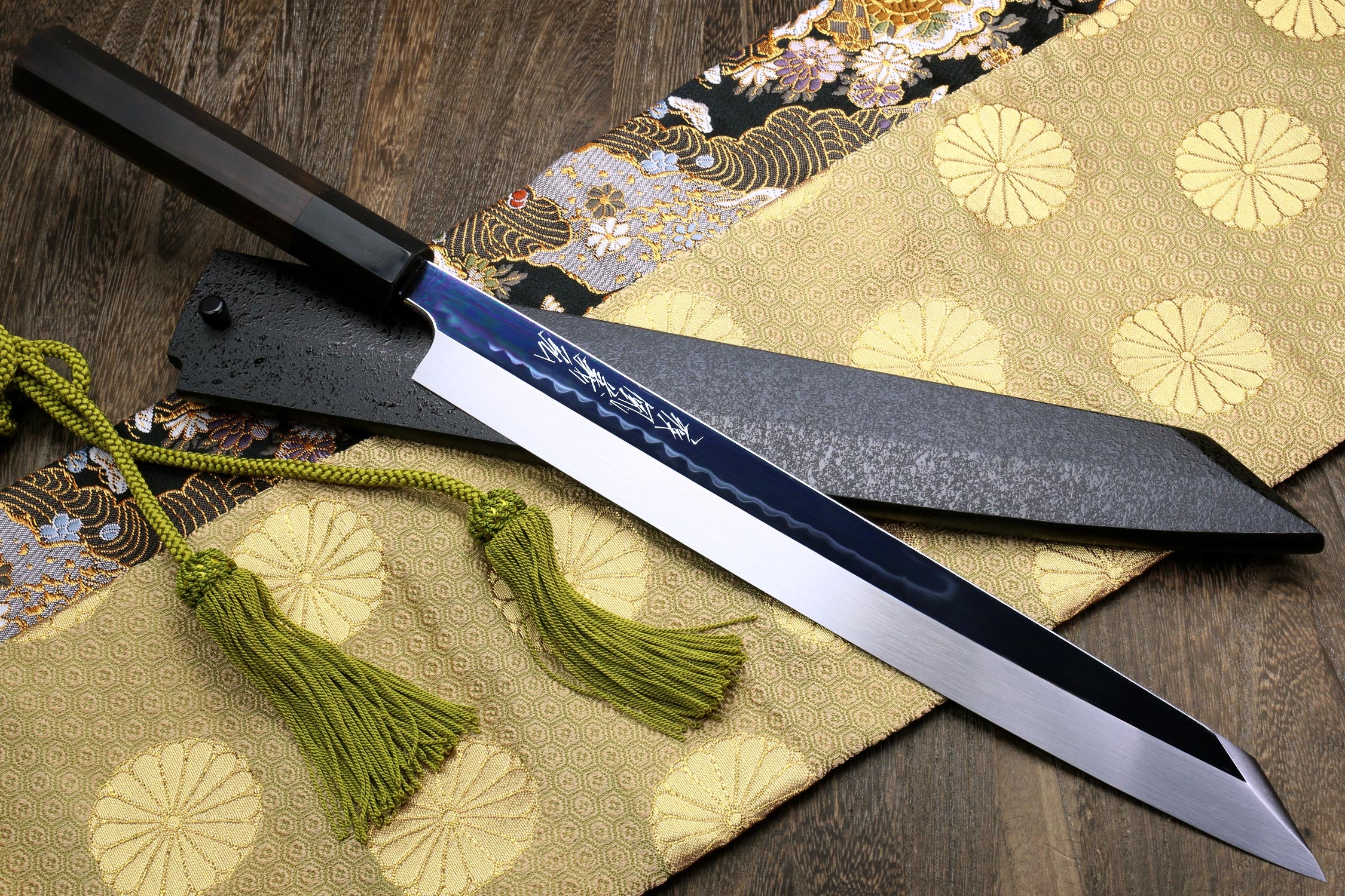 Japanese knife with silver mirrored blade and ebony handle, blue-black spine and tassel cord.