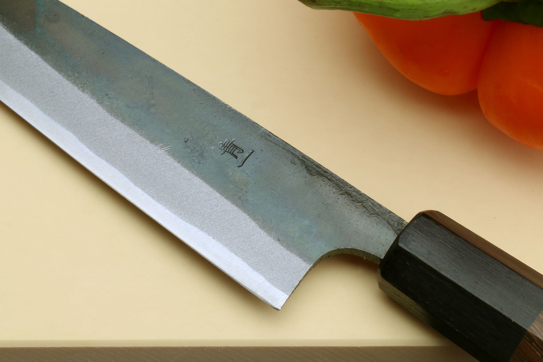 Kurouchi petty knife close-up of bolsters and dark shitan handle, blue blade
