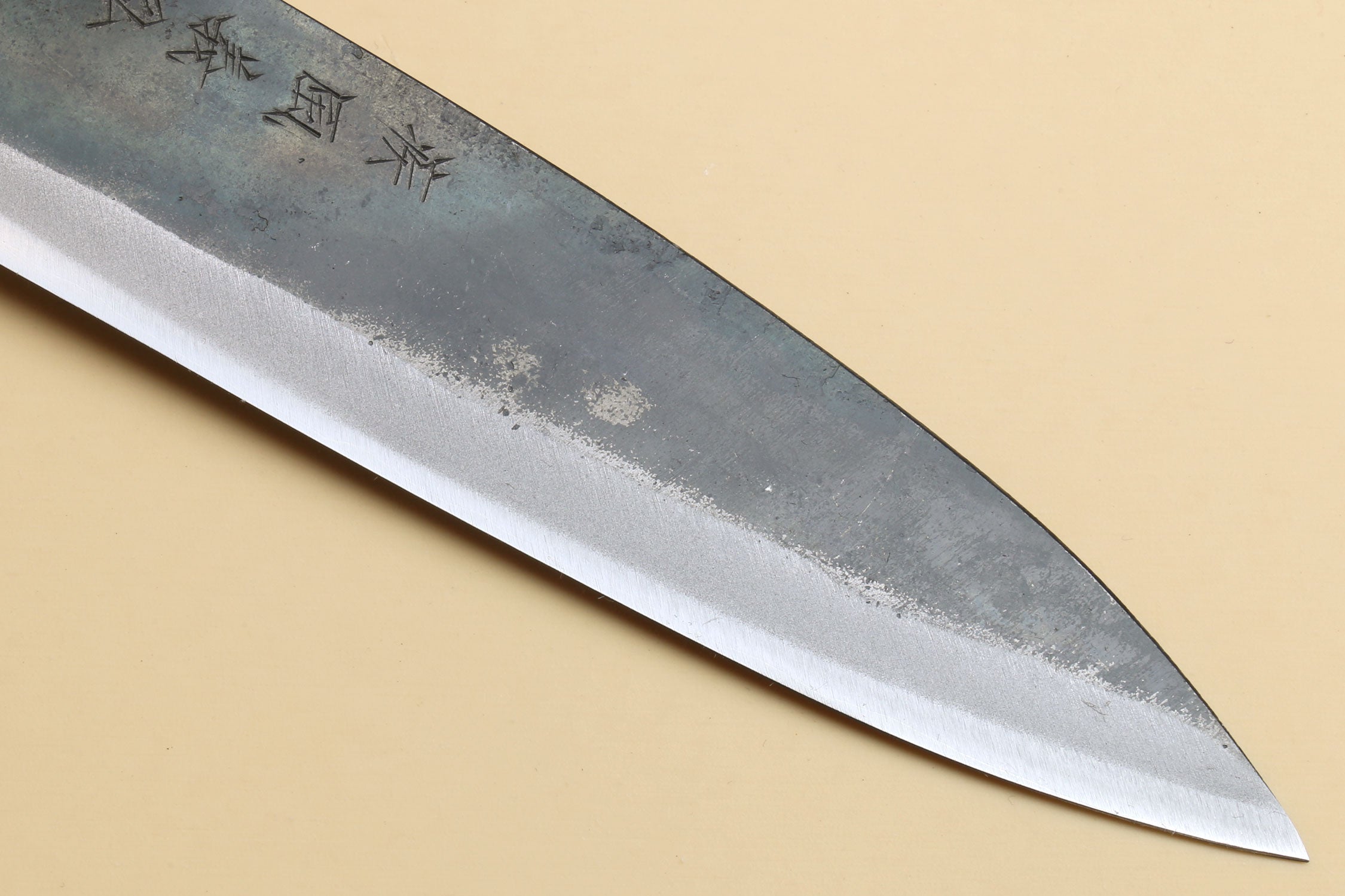 Kurouchi petty knife blade close-up, blue-gray high-carbon steel with etched marks